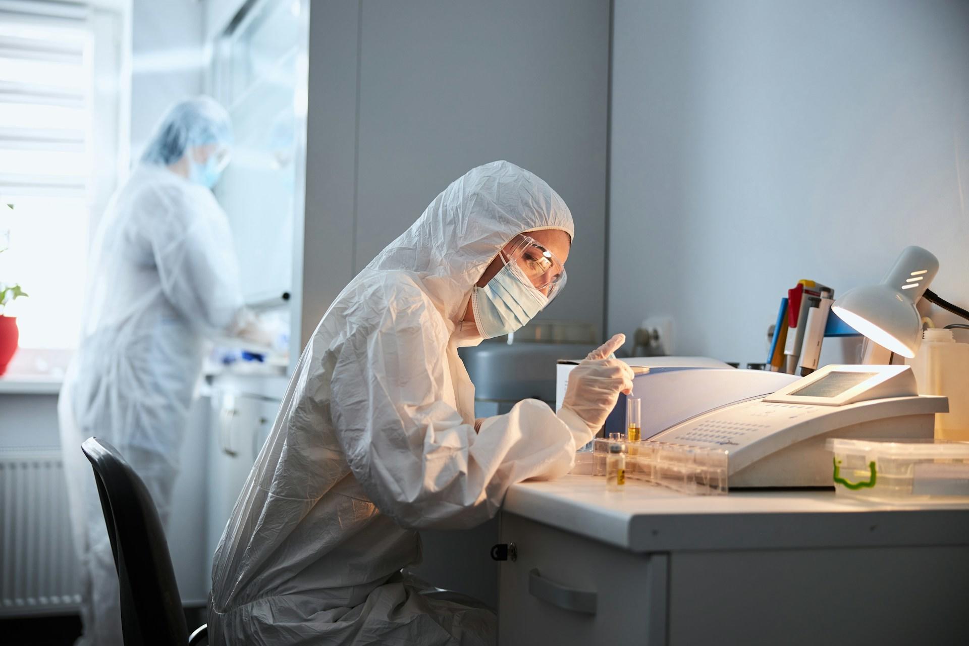 Two scientists in protective clothing working in a lab.