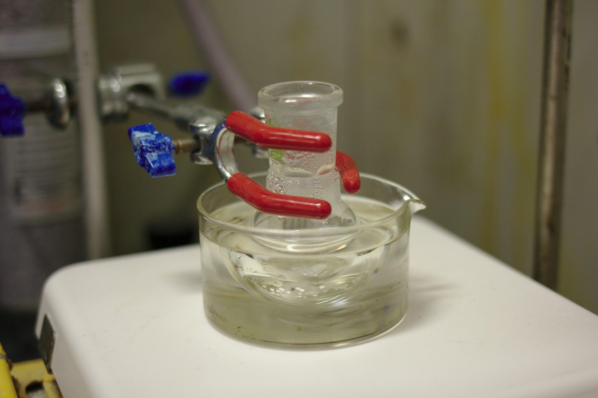 An experiment involving two glass vessels and a red clamp.