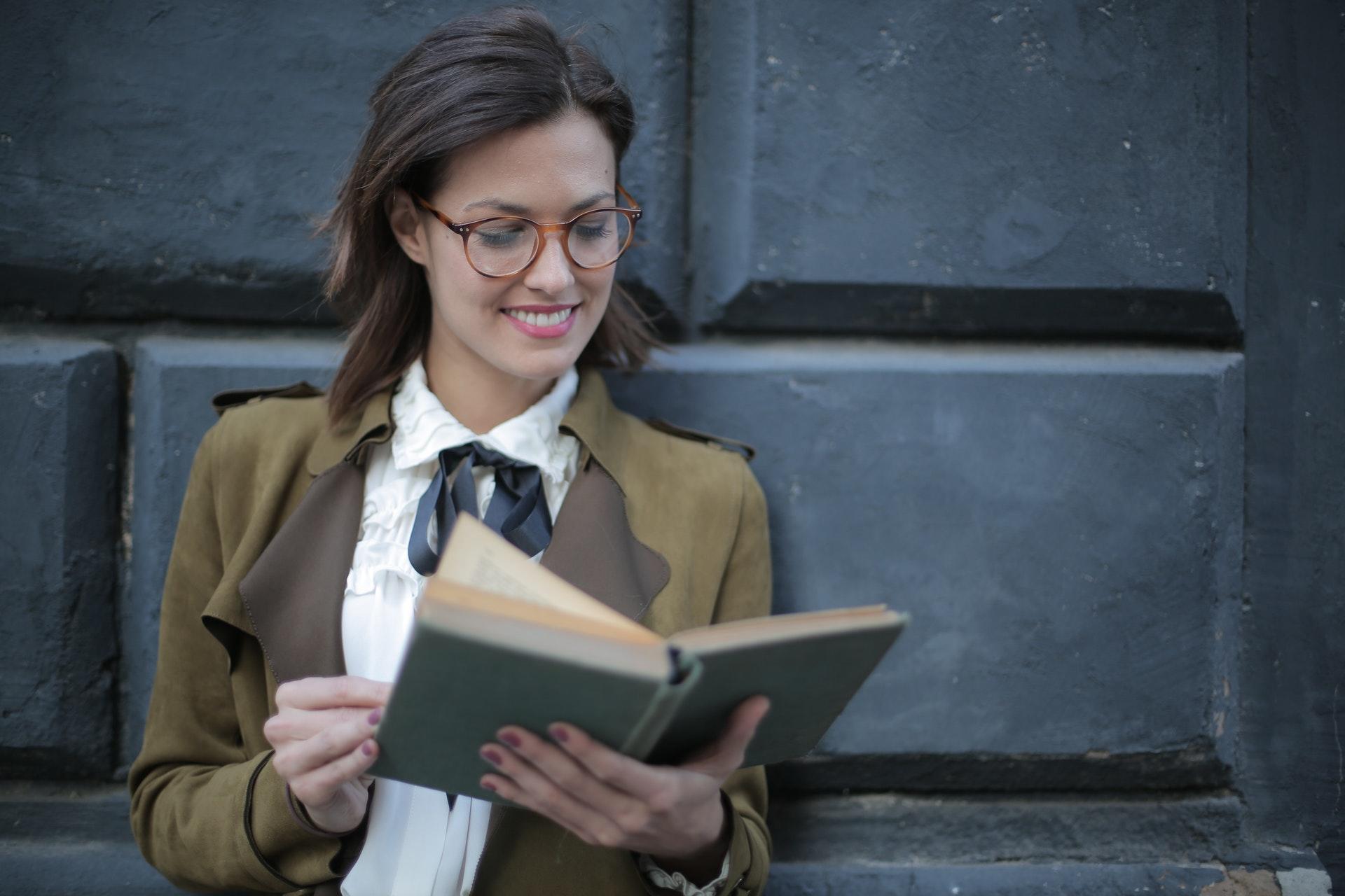 young woman smiles while reading book