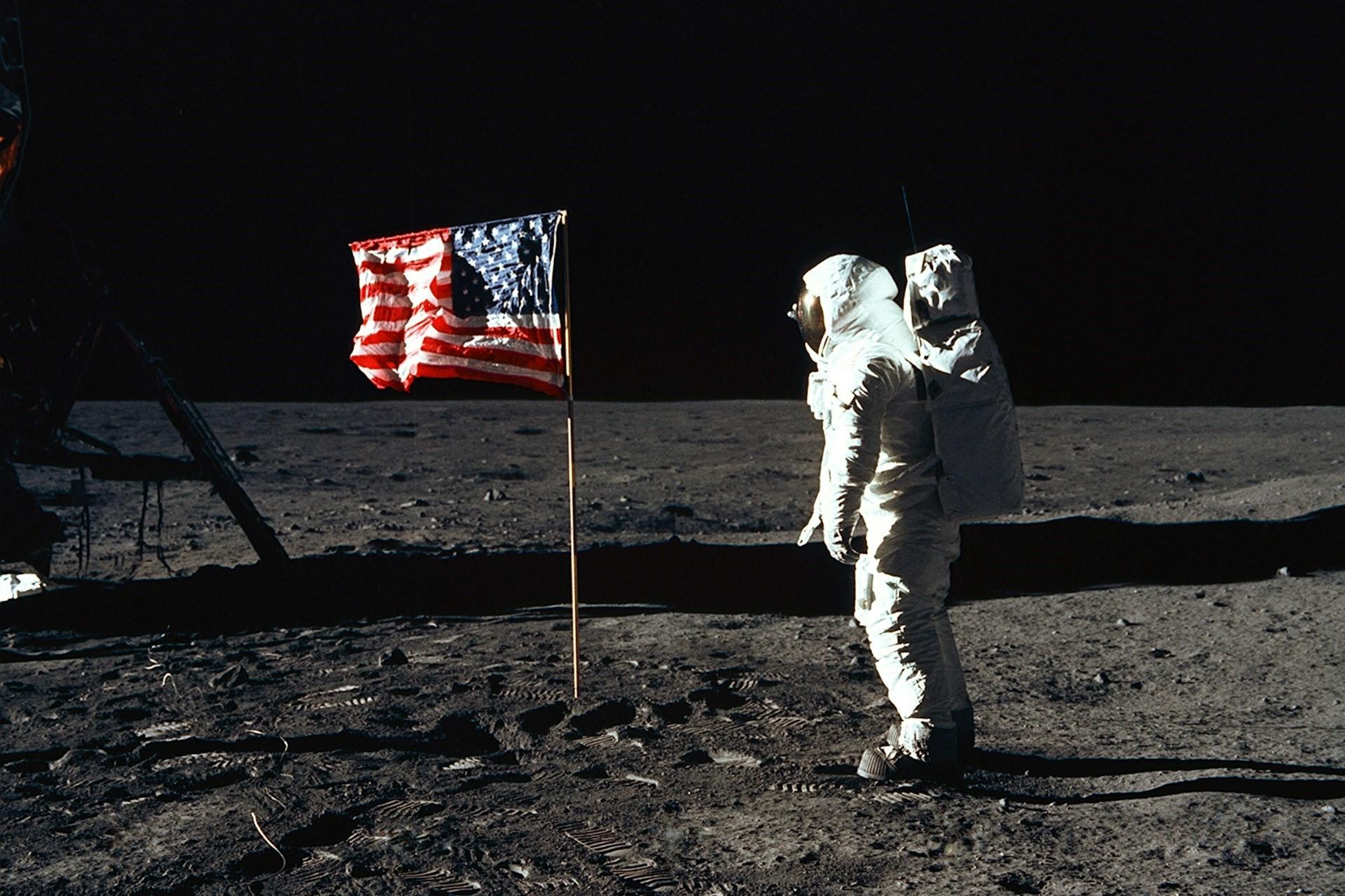 Buzz Aldrin looking at the American flag on the moon.