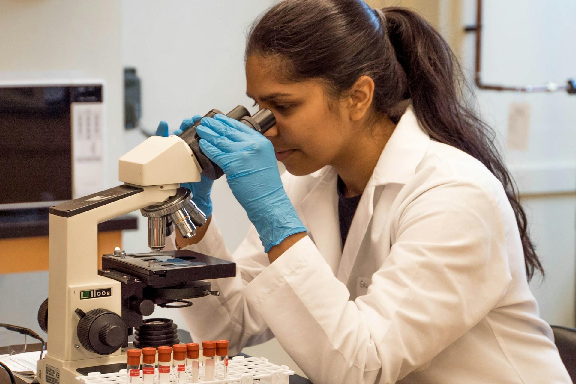 a woman using a microscope in a lab