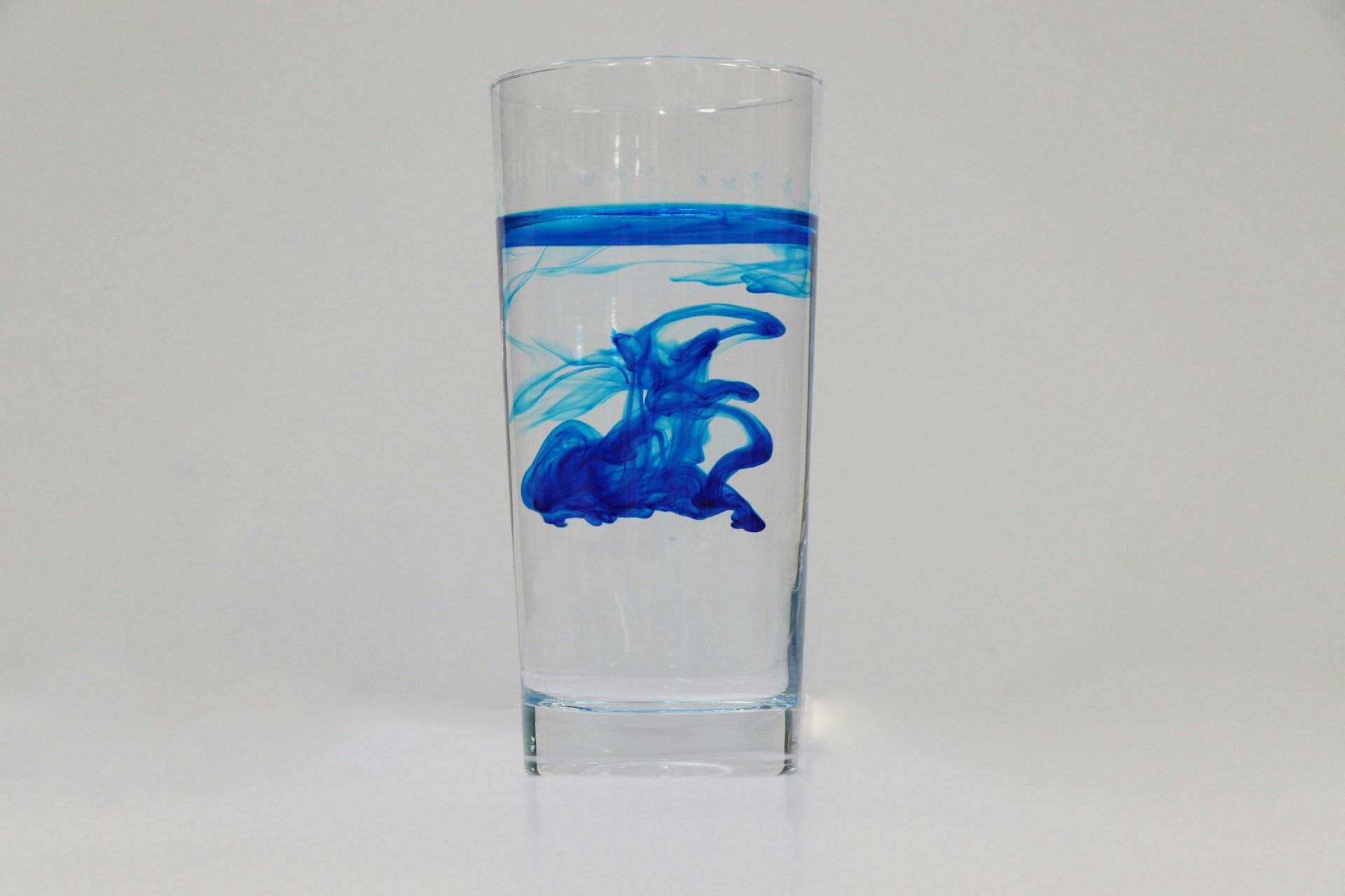 A transparent glass of water tinted with blue dye.