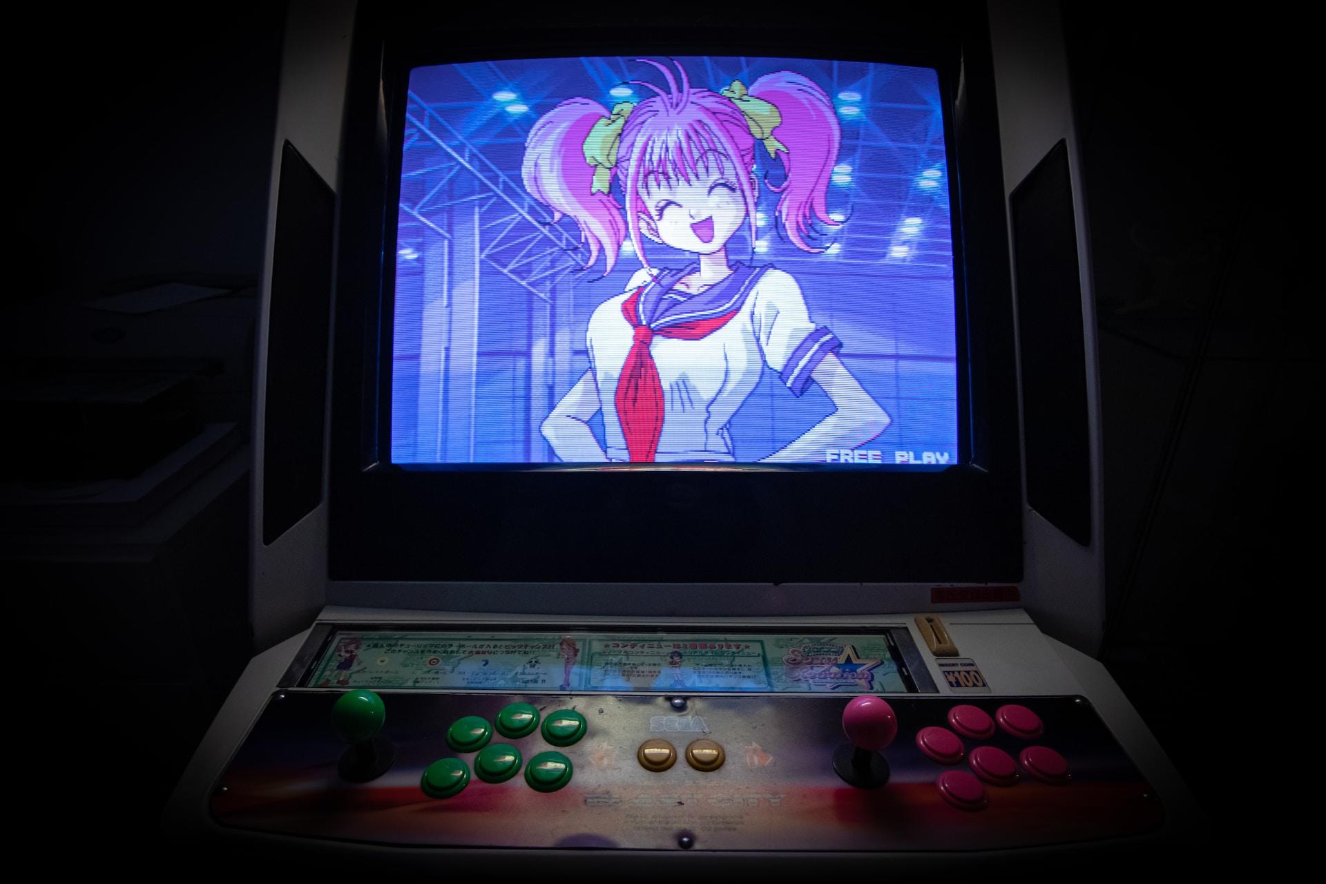 A computer game machine with red and green control buttons mounted on a console, which is overhung with a television displaying pink-haired Sailor Moon against a blue background. 
