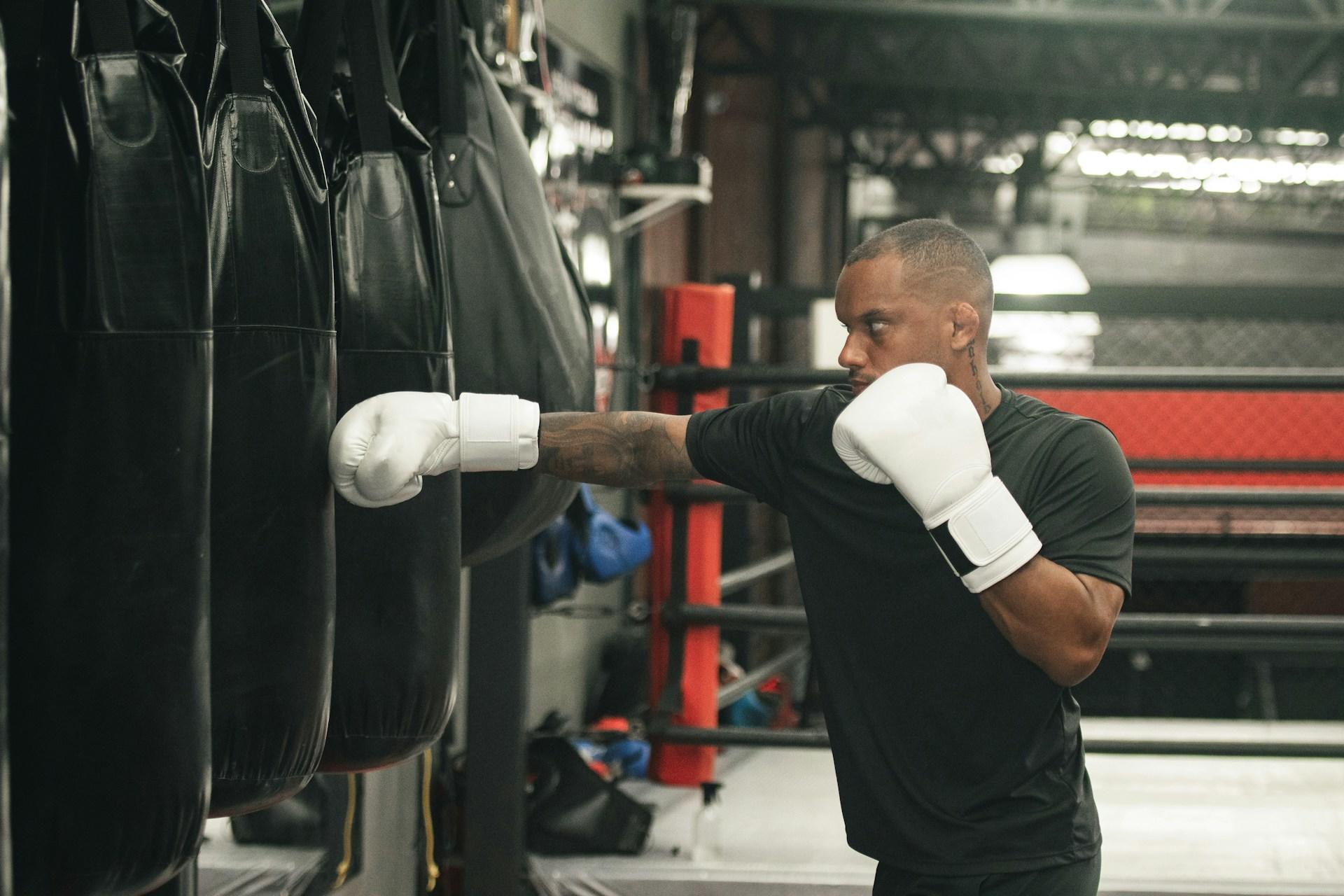 A man wearing boxing gloves punching a punching bag in a gym.