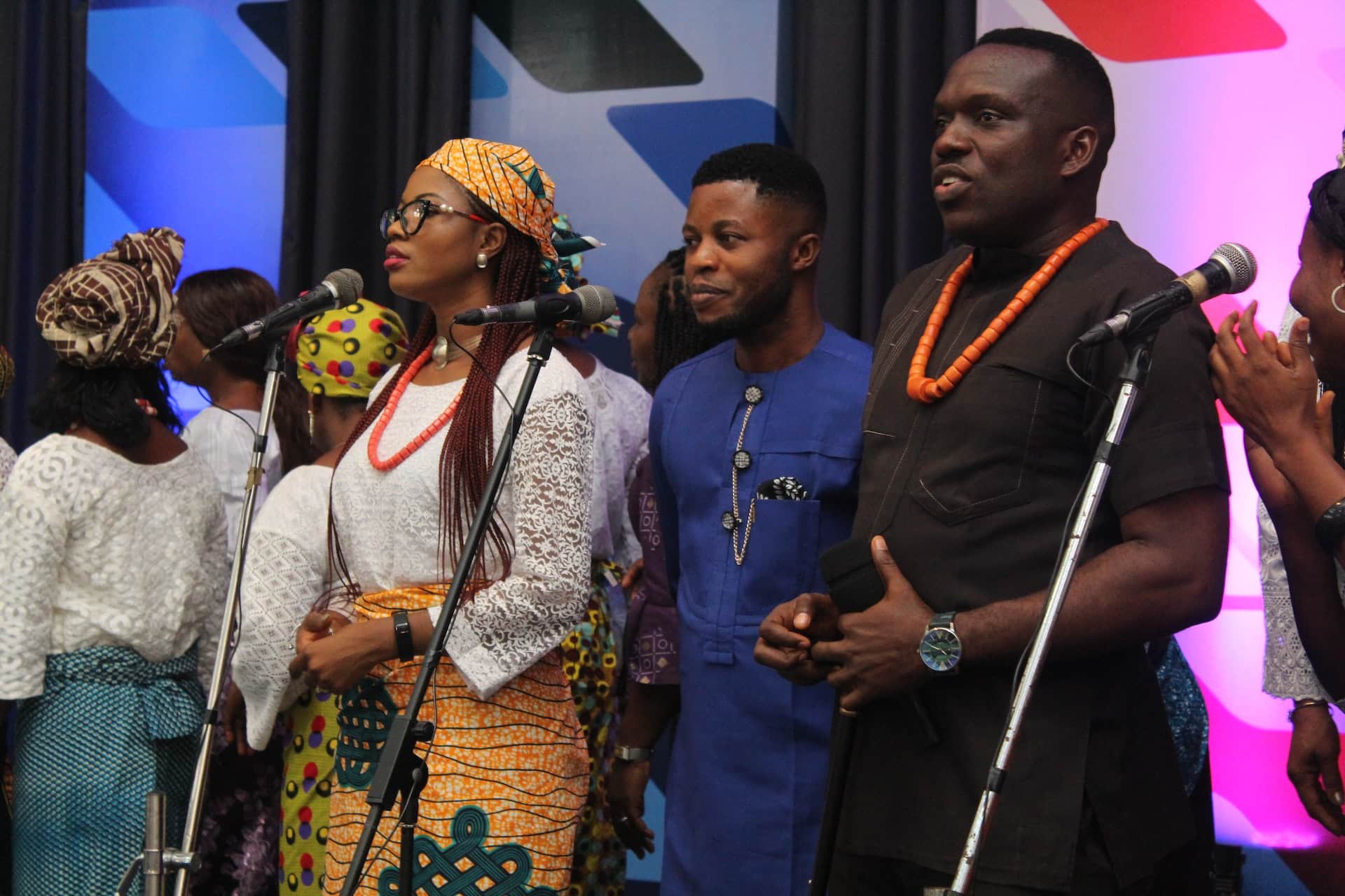 A group of people, casually dressed, standing in front of three microphones