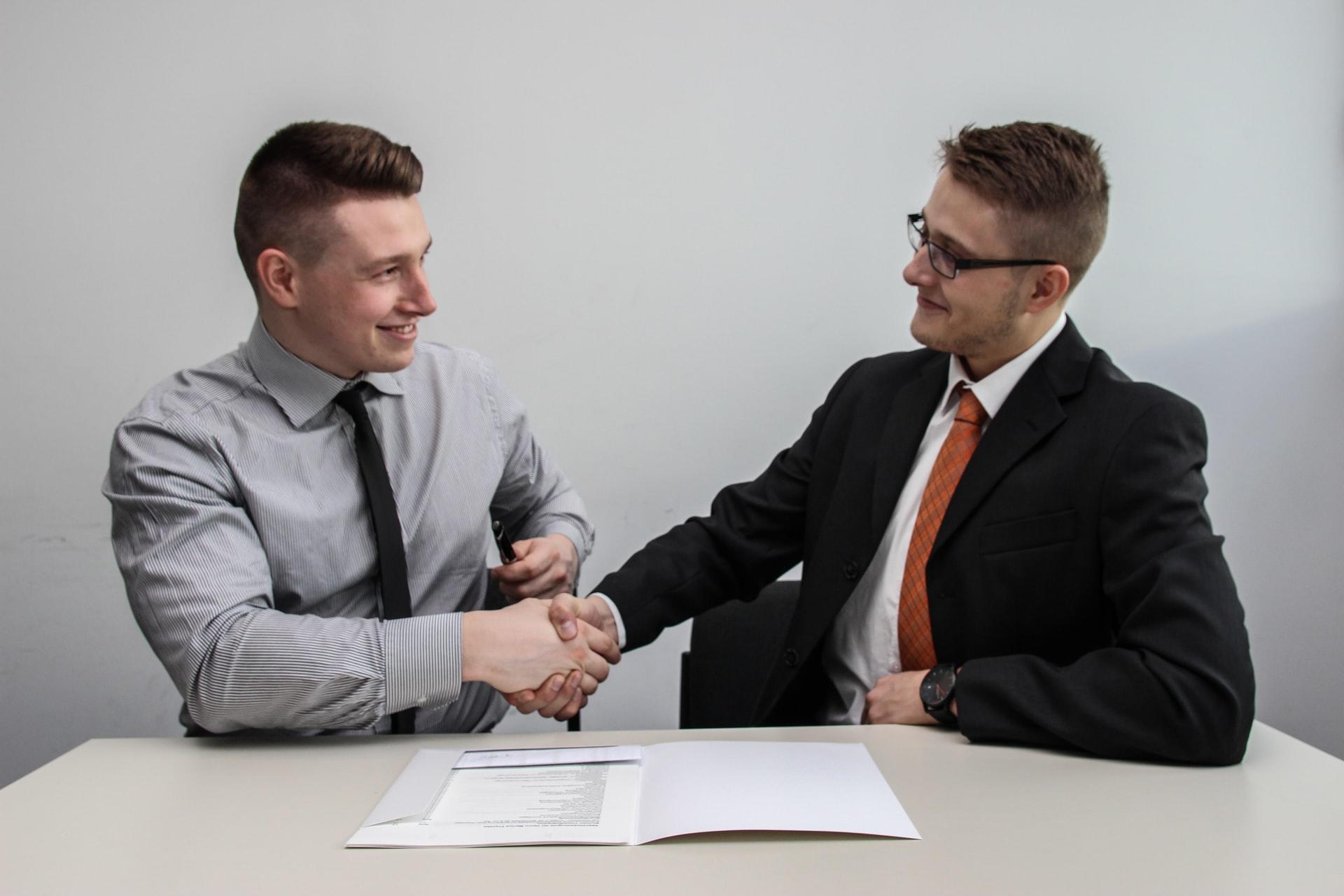 Two people shaking hands against an office background
