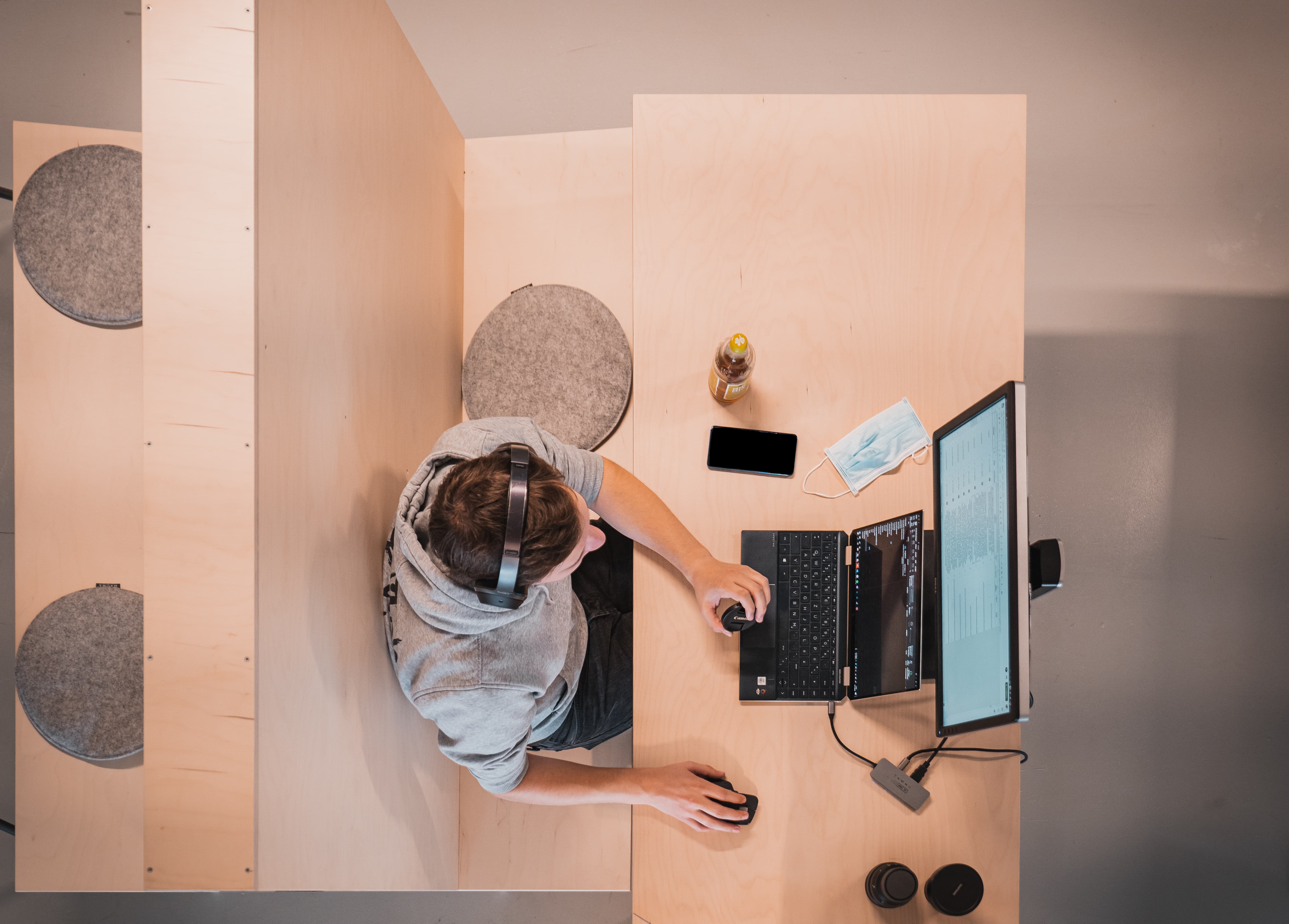 Man in headphones writing code on computer with two displays