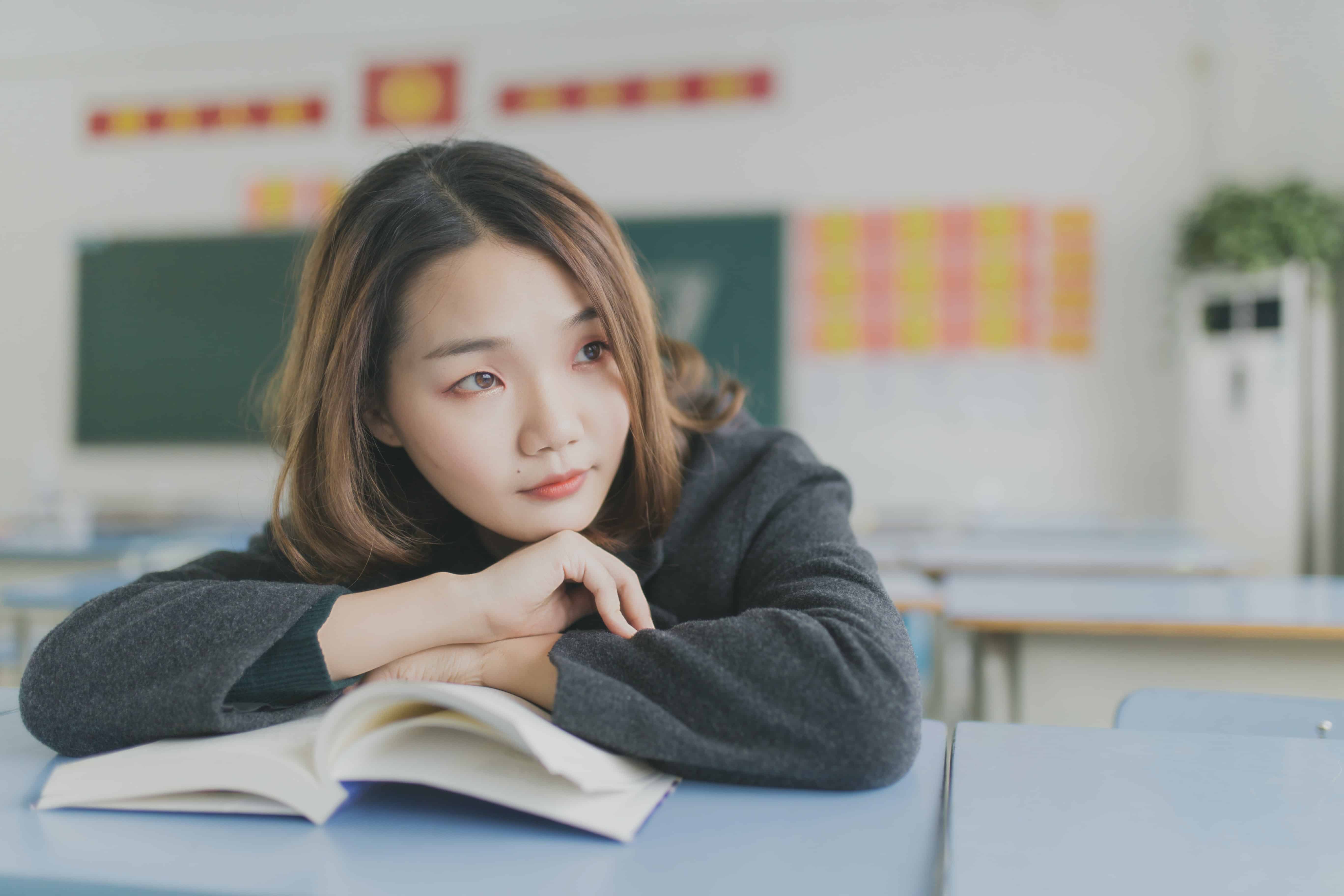 female student sitting at desk with a book