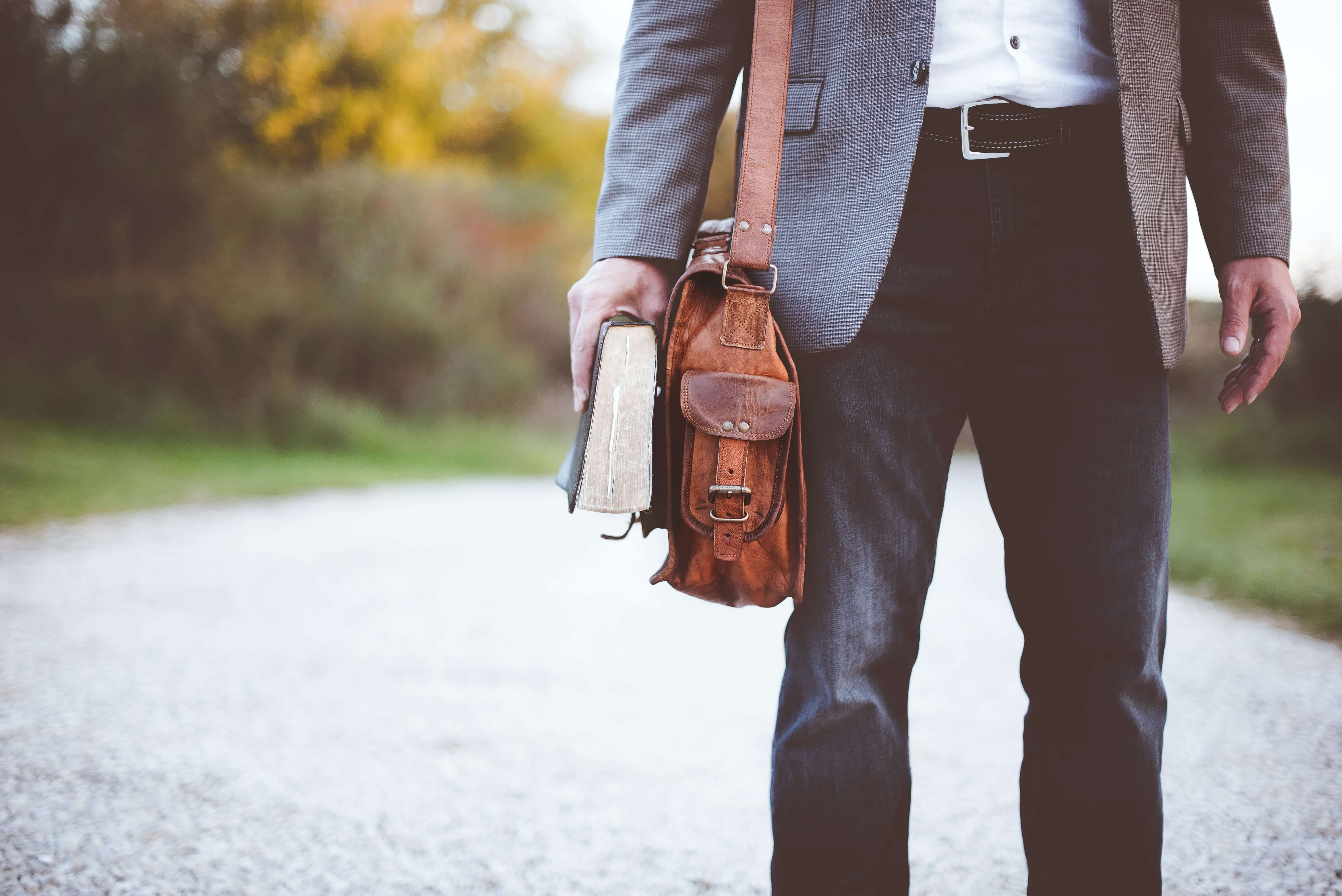 Man with a leather satchel holding a book