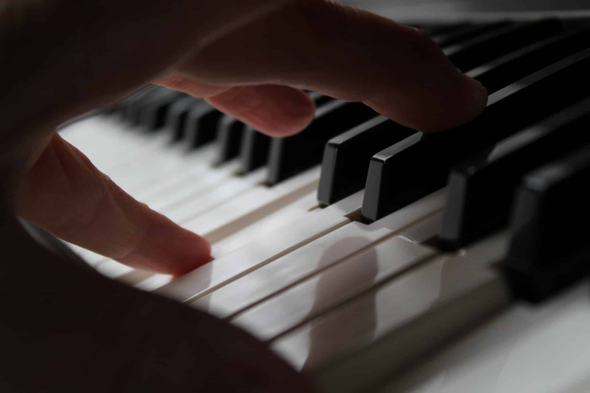 A closeup of a hand with its fingers striking the piano keys.