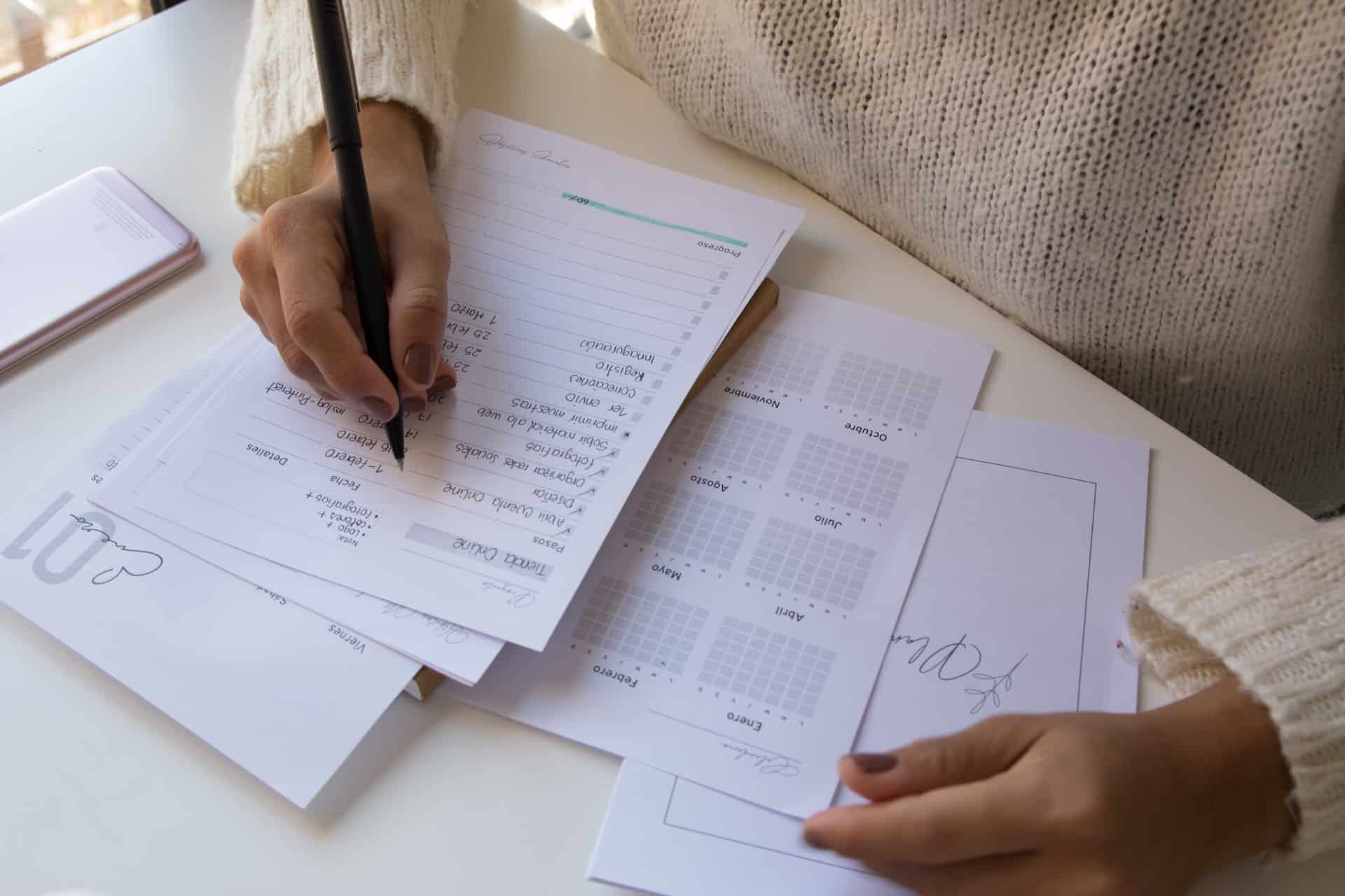 A person in a white shirt writing note in a monthly planner