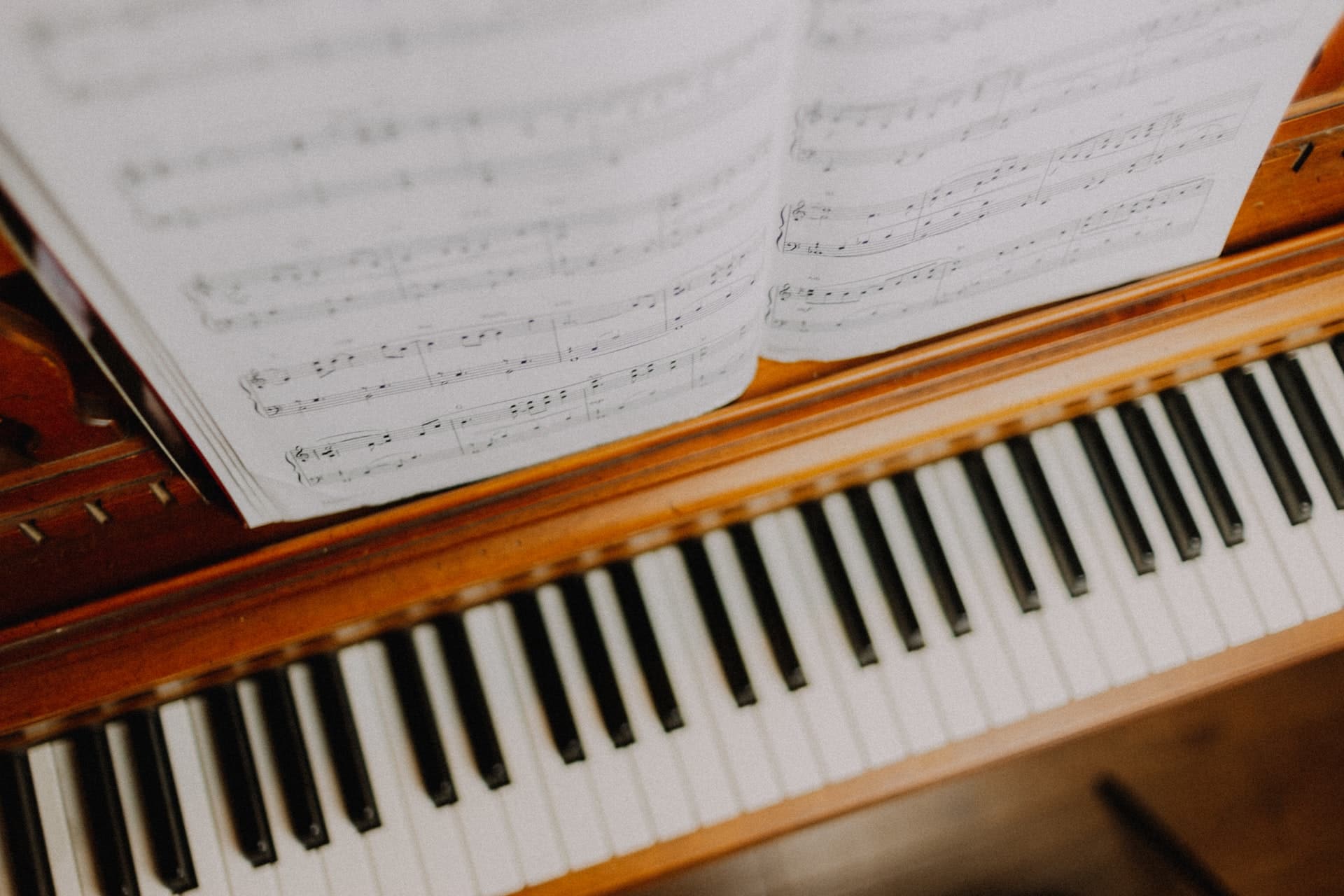 An open blond wood upright piano with sheet music on the rest