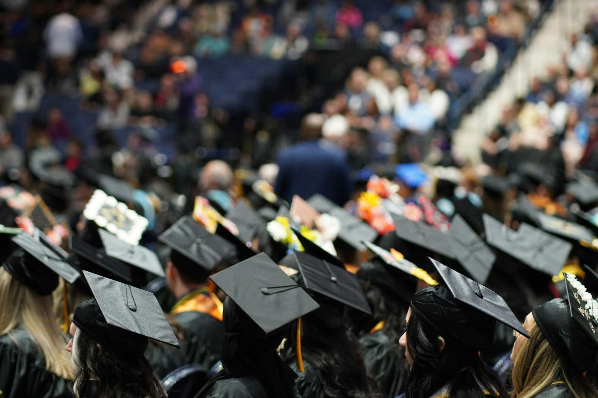 Graduates wearing black academic gowns and mortarboards at a graduation ceremony