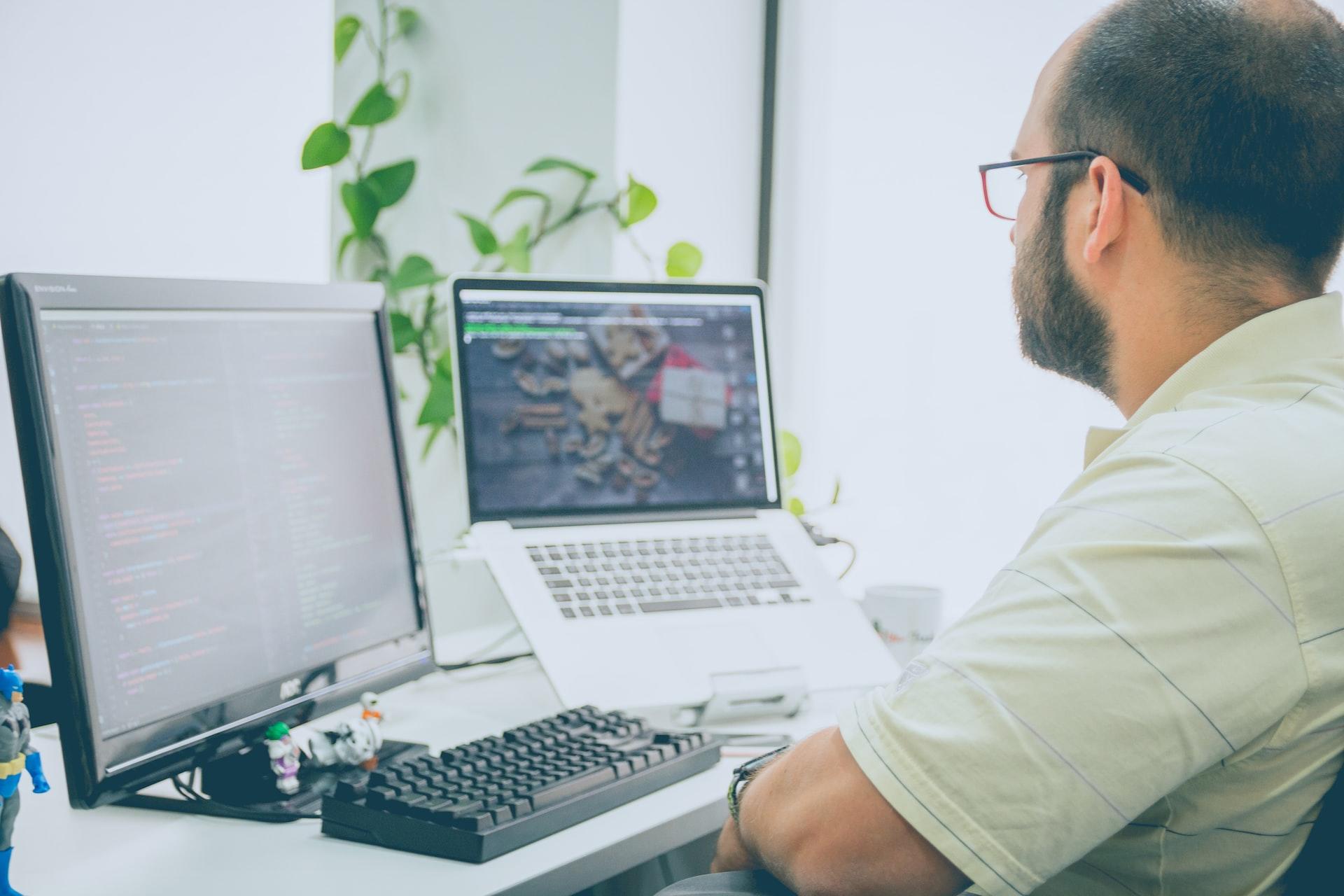 Man sitting at a computer with lines of code on it