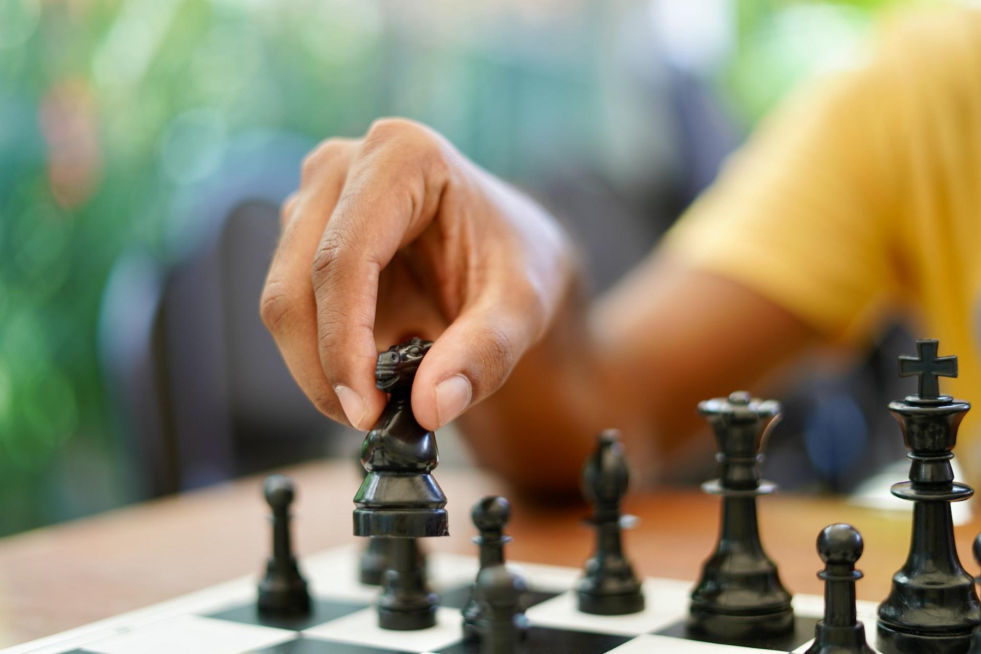 Person moving black knight in a game of chess