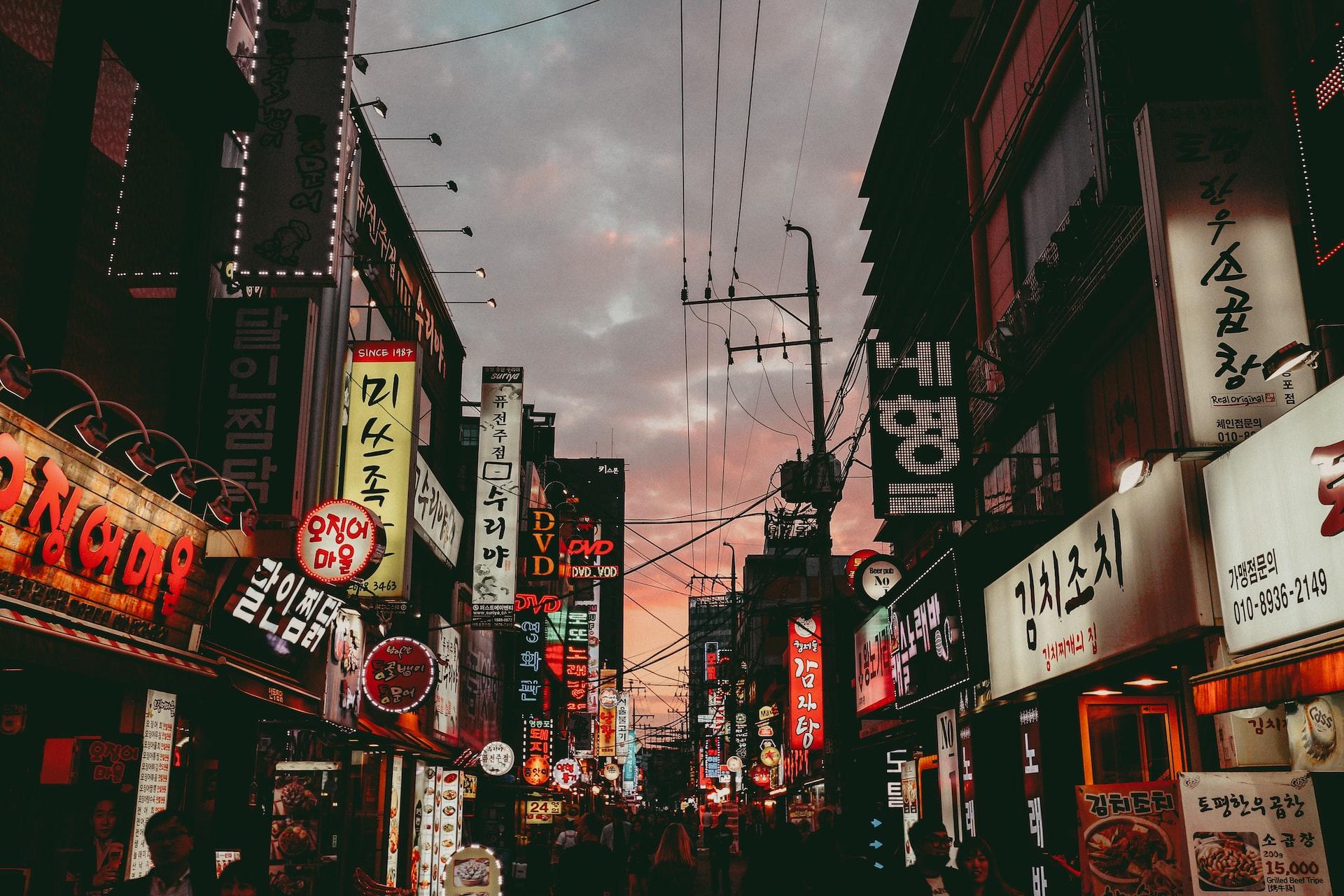 And entertainment alley in South Korea at dusk with signs lit up and power lines gridded through