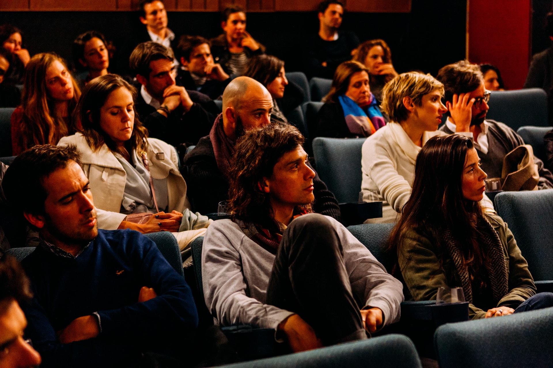 A group of people sitting in a darkened auditorium, focused on the same perspective.