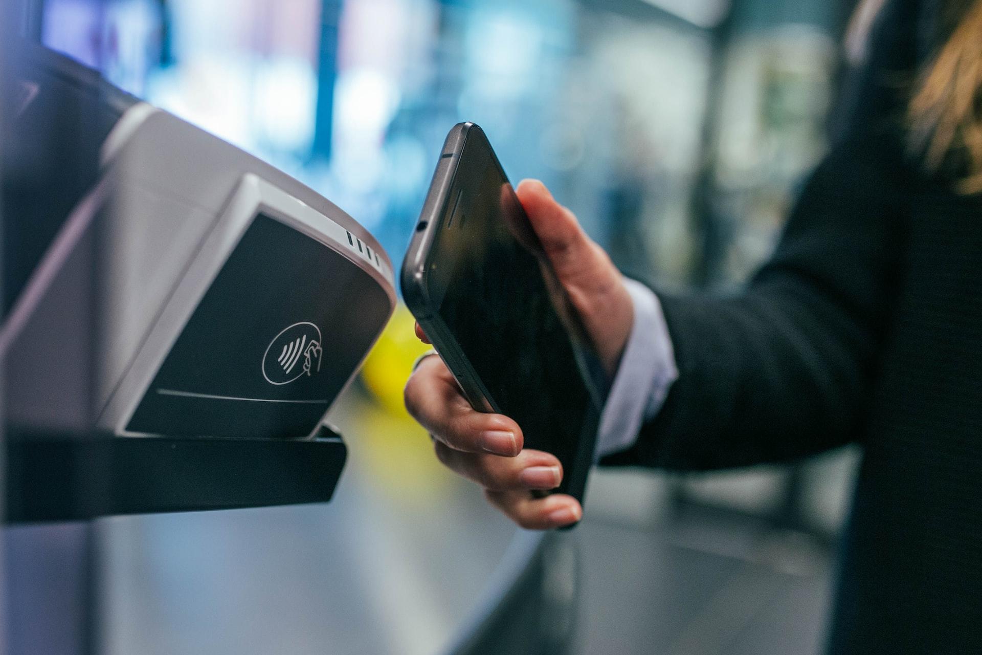 Person holding smartphone by payment terminal.
