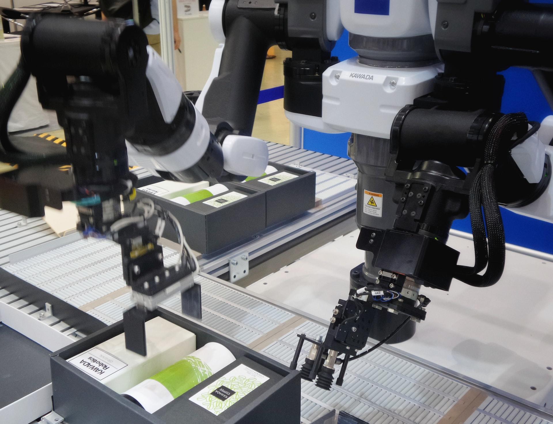 Three robotic arms package products on an assembly line. 