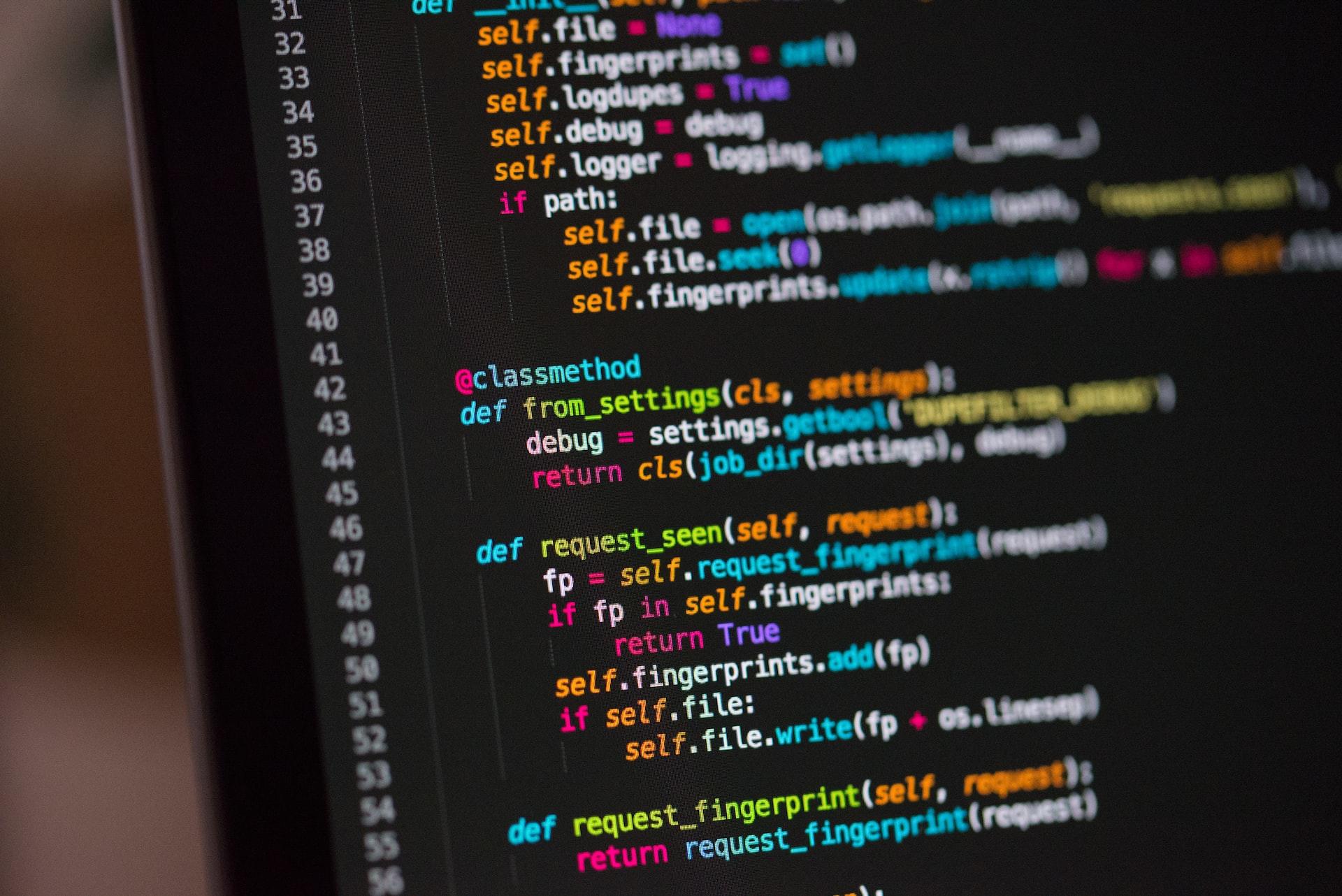 The left side of a computer monitor displaying colourful lines of code with readable syntax.