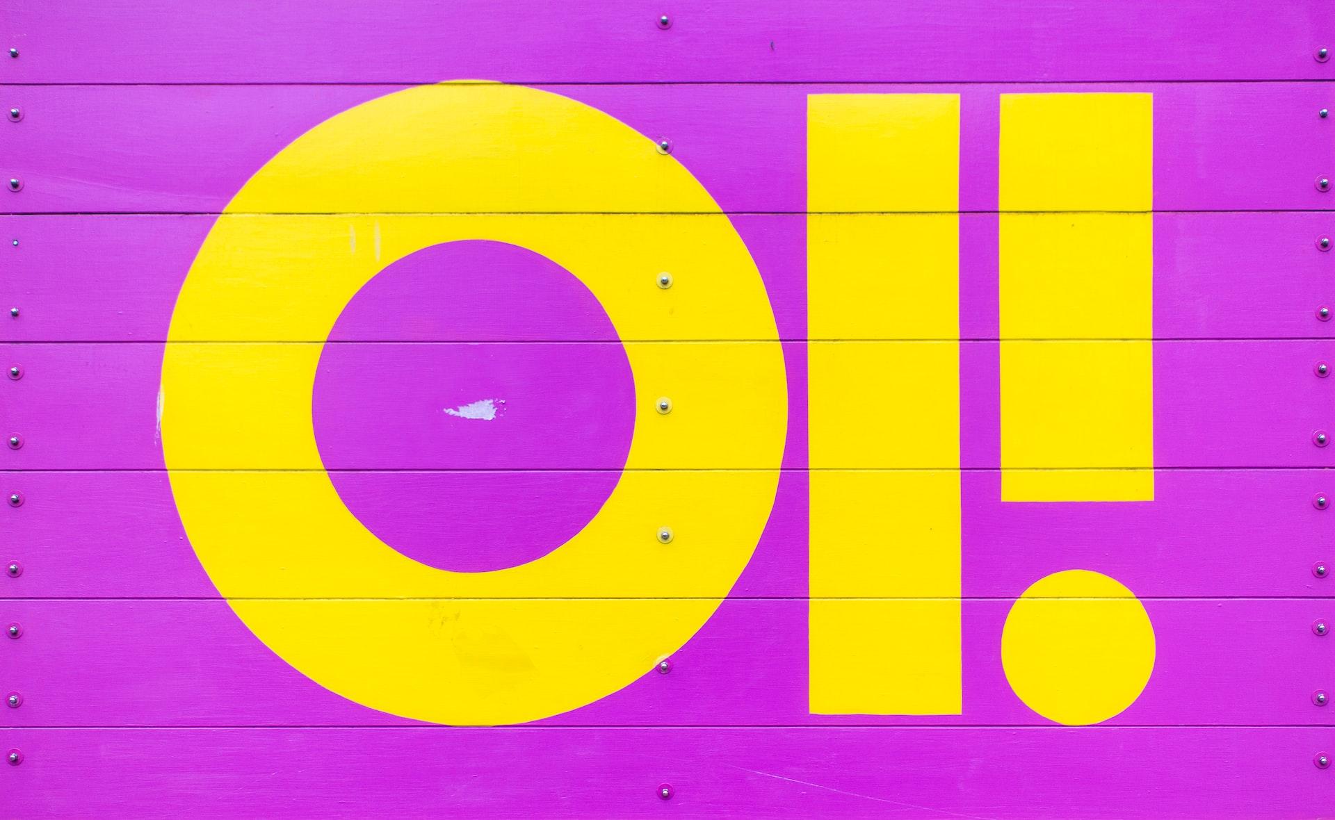 A bright yellow is used to point Oi! on a hot pink background on what appears to be a garage door. 