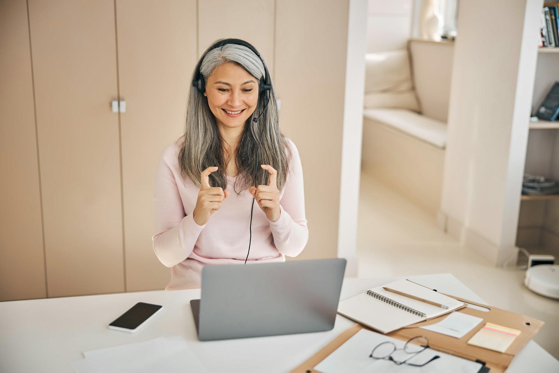 A woman wearing a headset sits at a desk, focused on her laptop.
