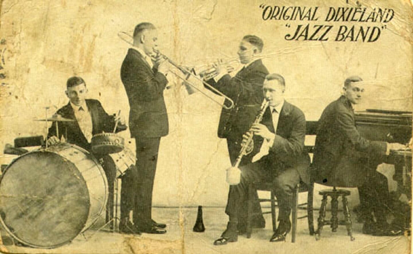 A group of men in suits with musical instruments looking keen to play them.