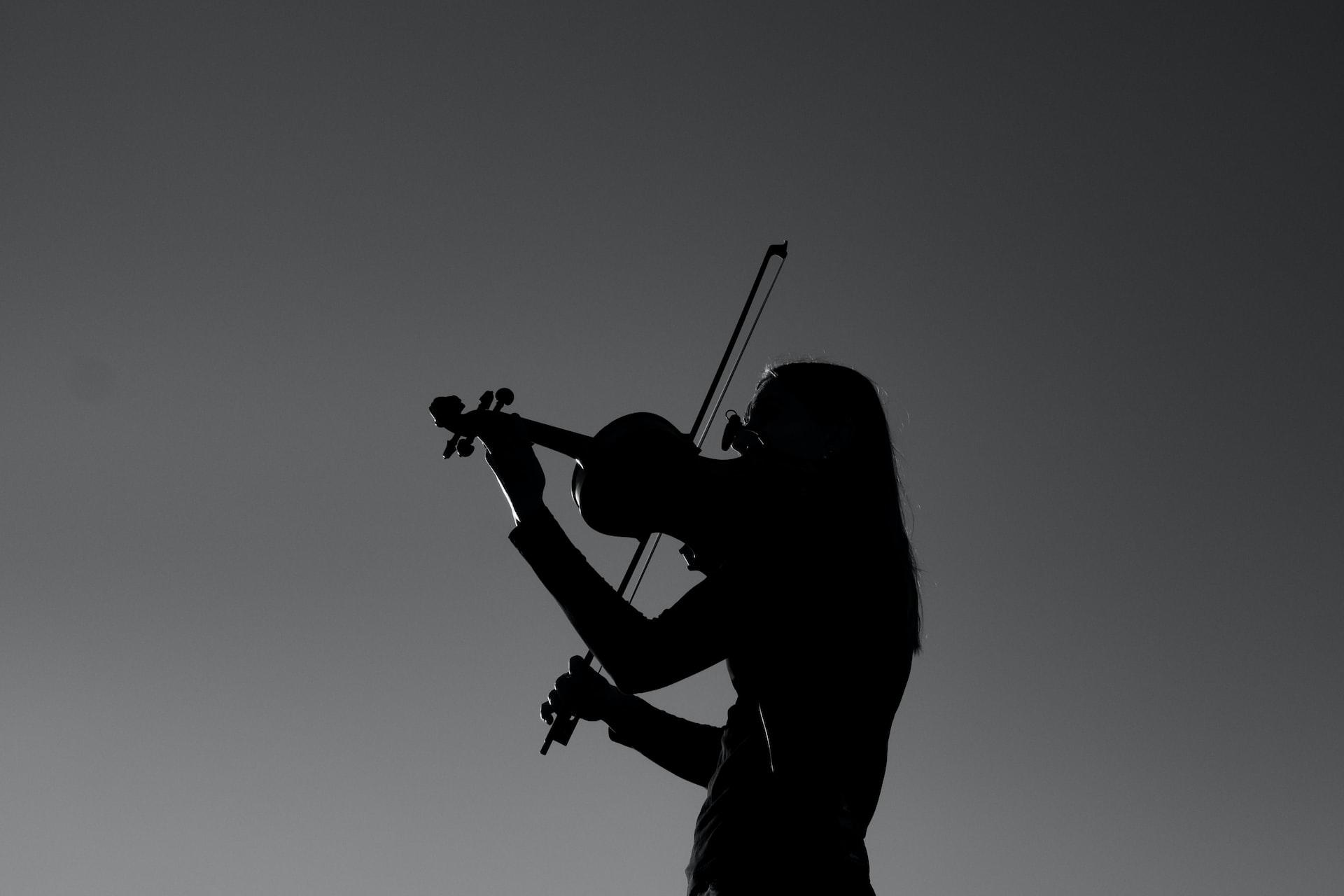 A greyscale photo of a silhouetted violinist