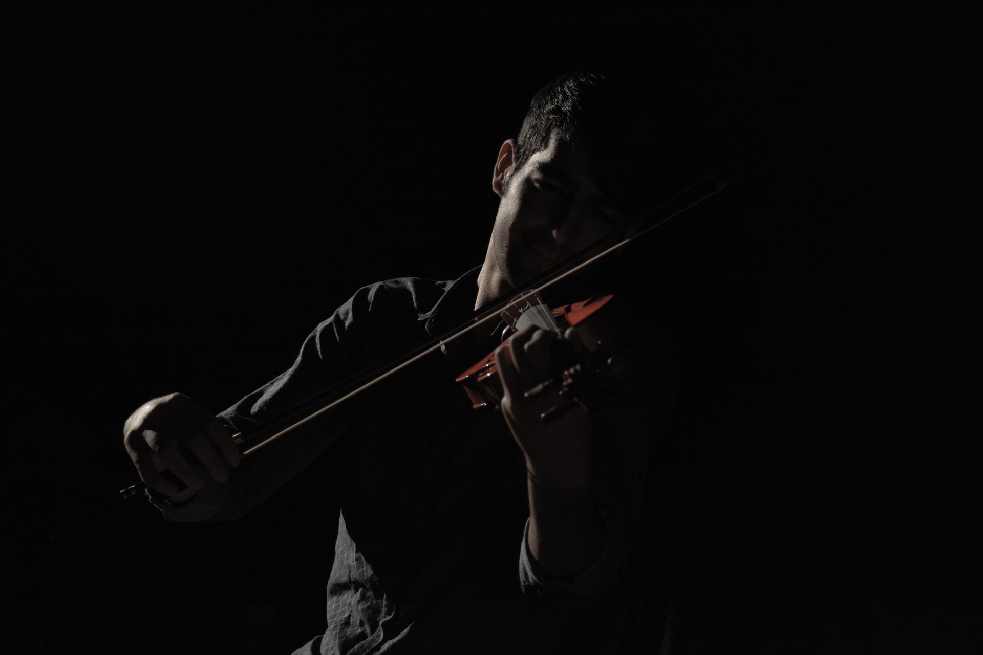 A shot of a man playing the violin in the dark