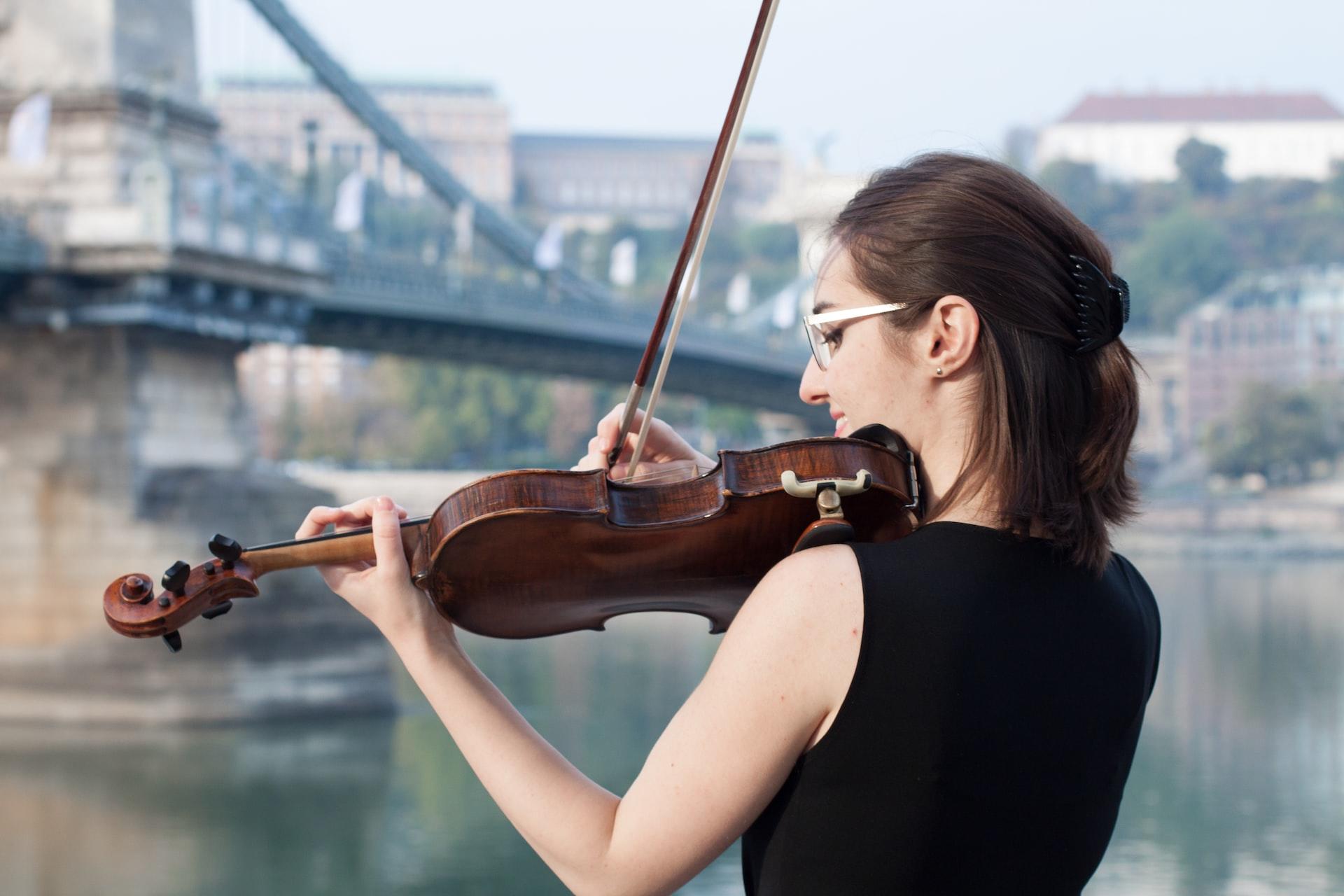 A violinist playing by a bridge