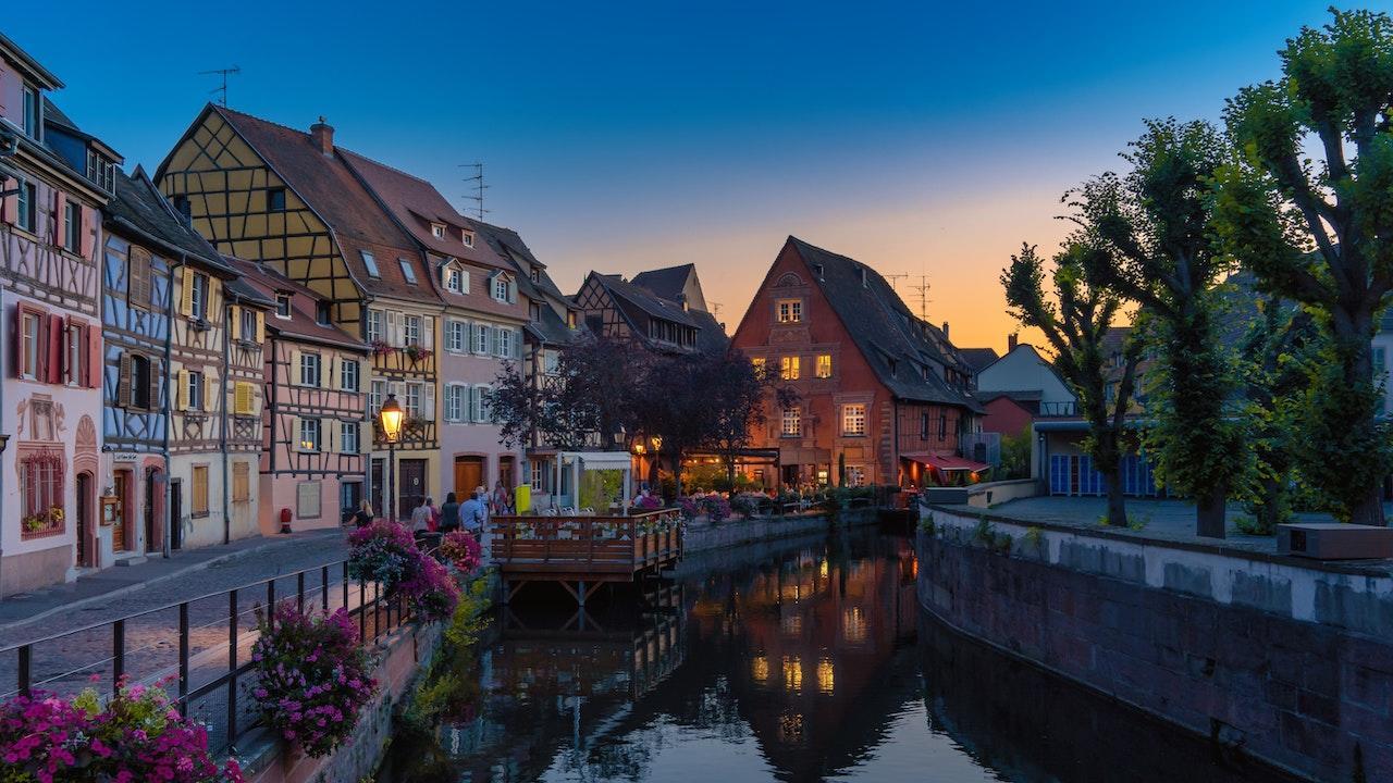 An evening sky over rustic French cottage homes and a river.