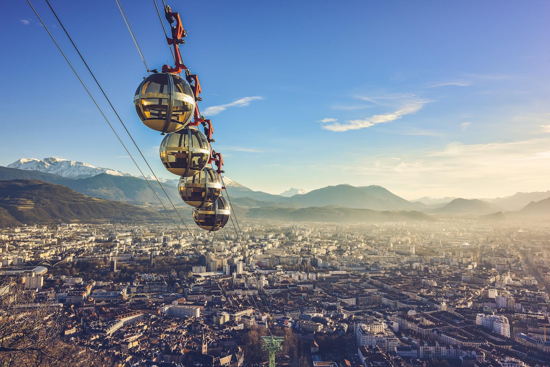 A spherical cable car travels up to the top of a mountain over the city of Grenoble.