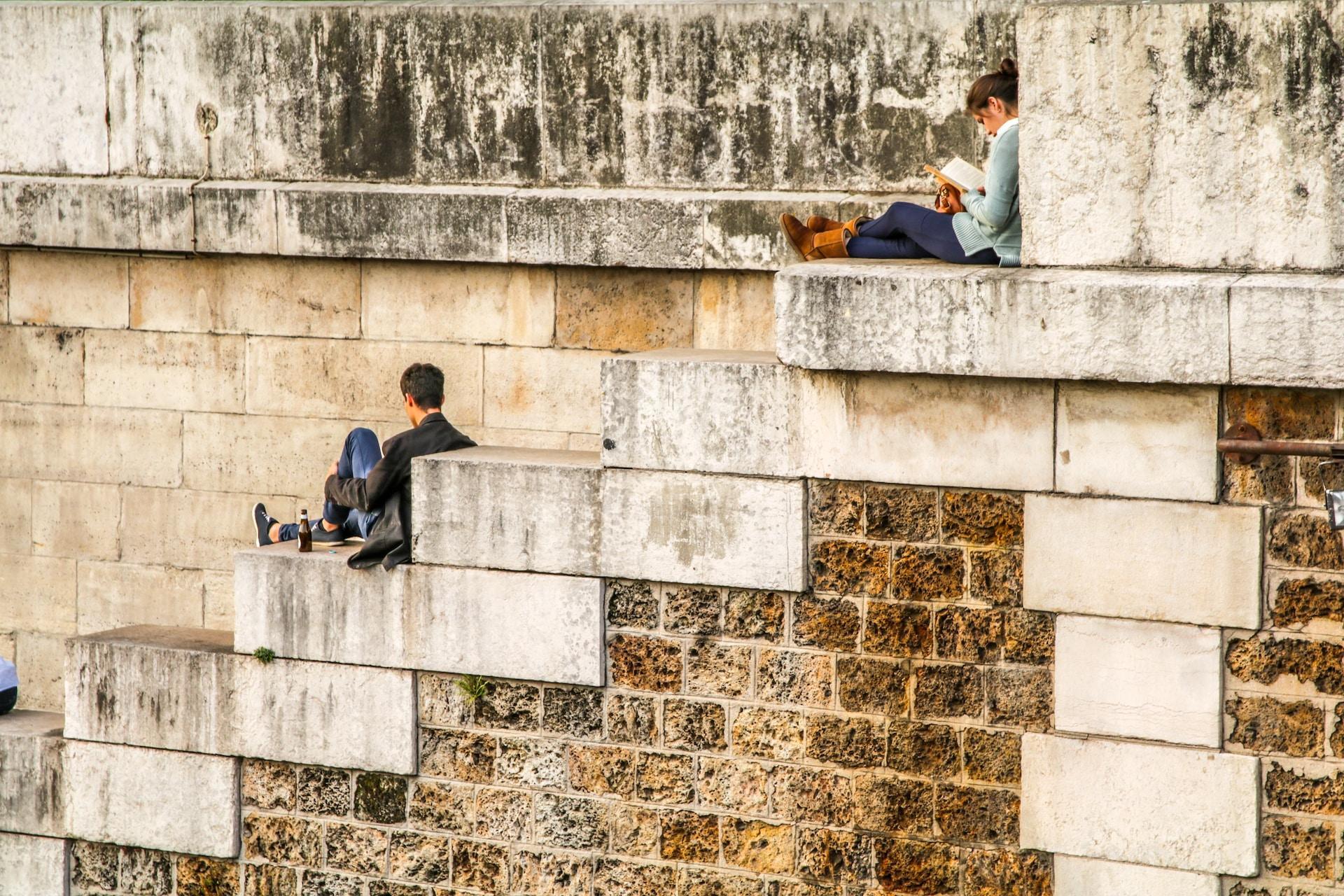 Students relax on the brick wall bordering the Seine, on blocks big enough to sit on.
