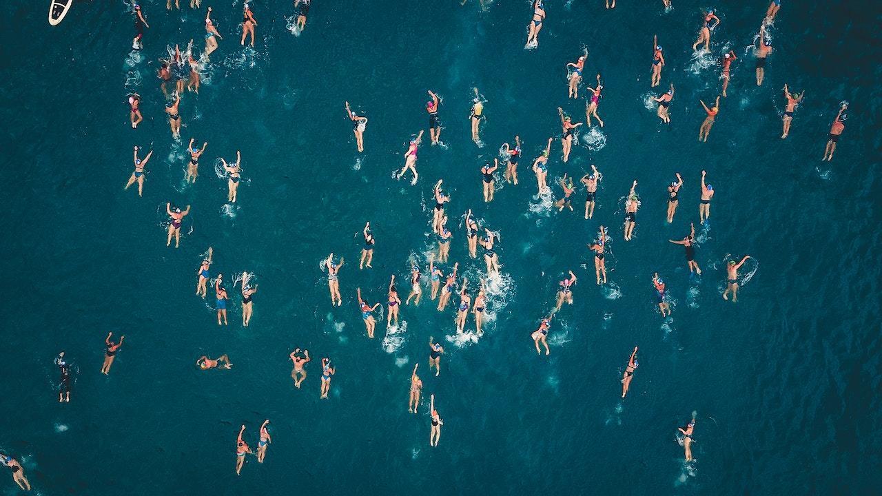 An aerial view of many people swimming in blue water.