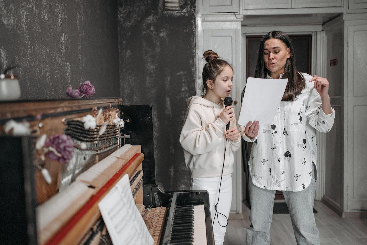 A tween student practices singing with her vocal teacher.