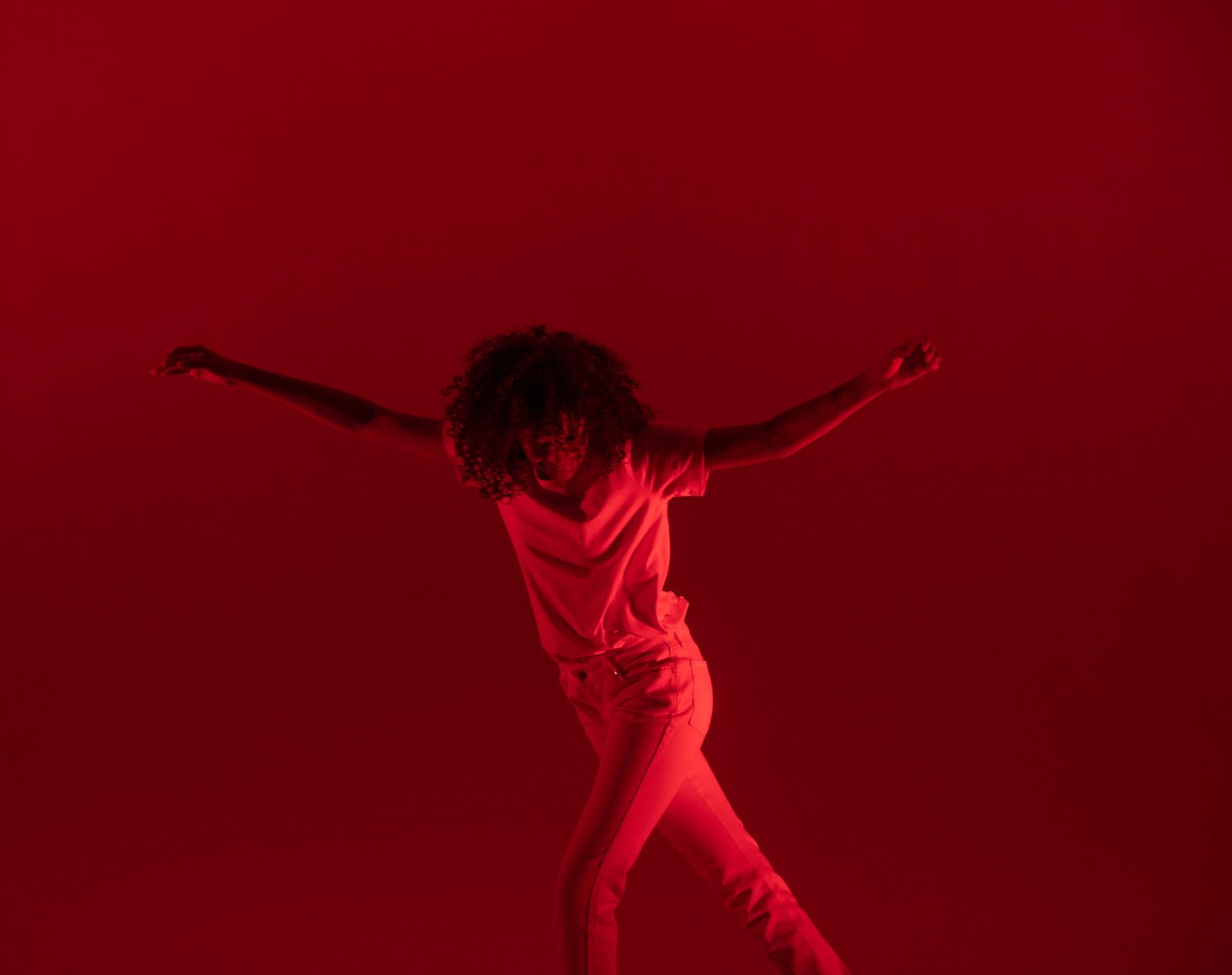 A woman dancing lit up in red