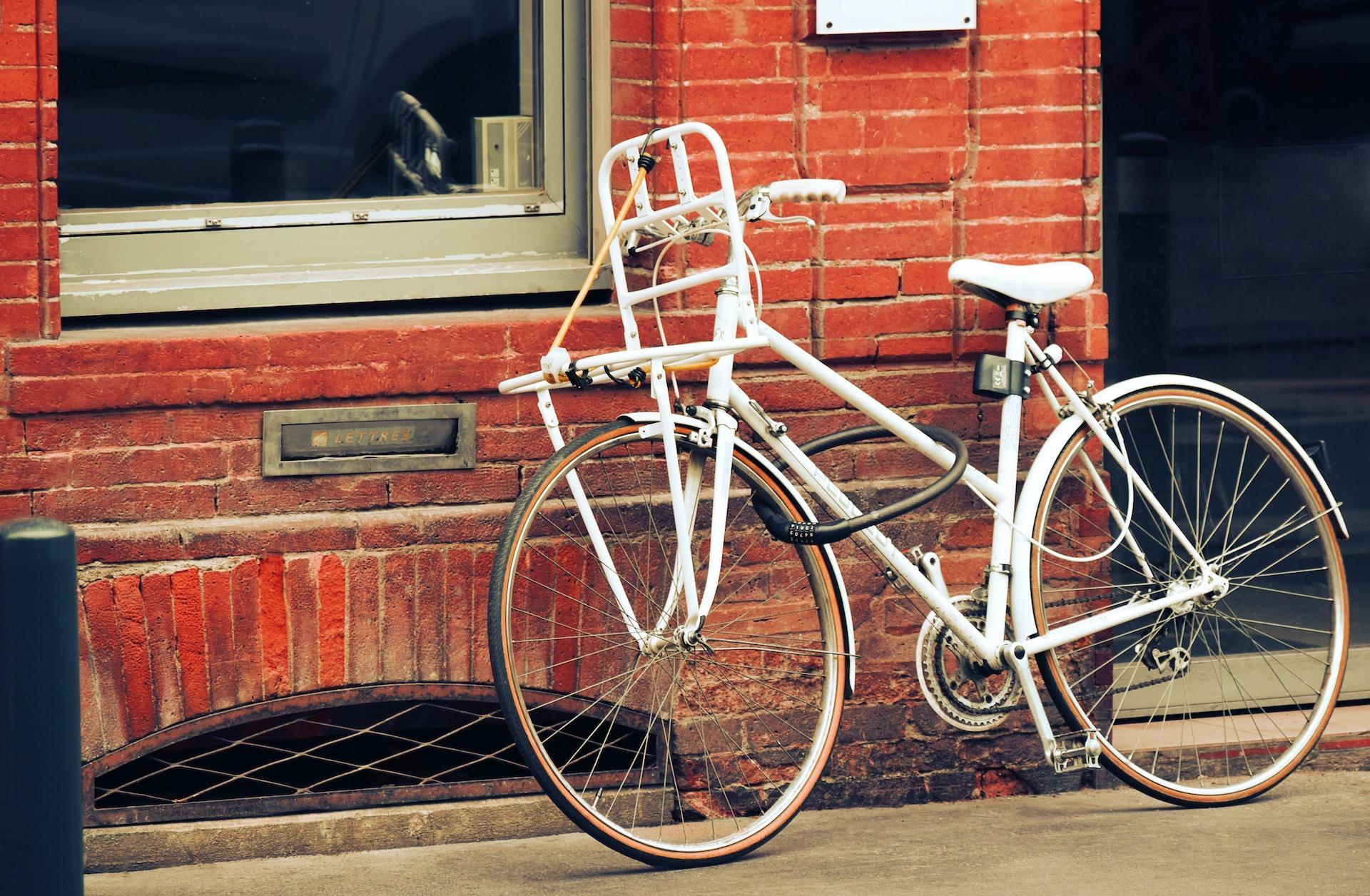 A white bicycle leans against a brick building.