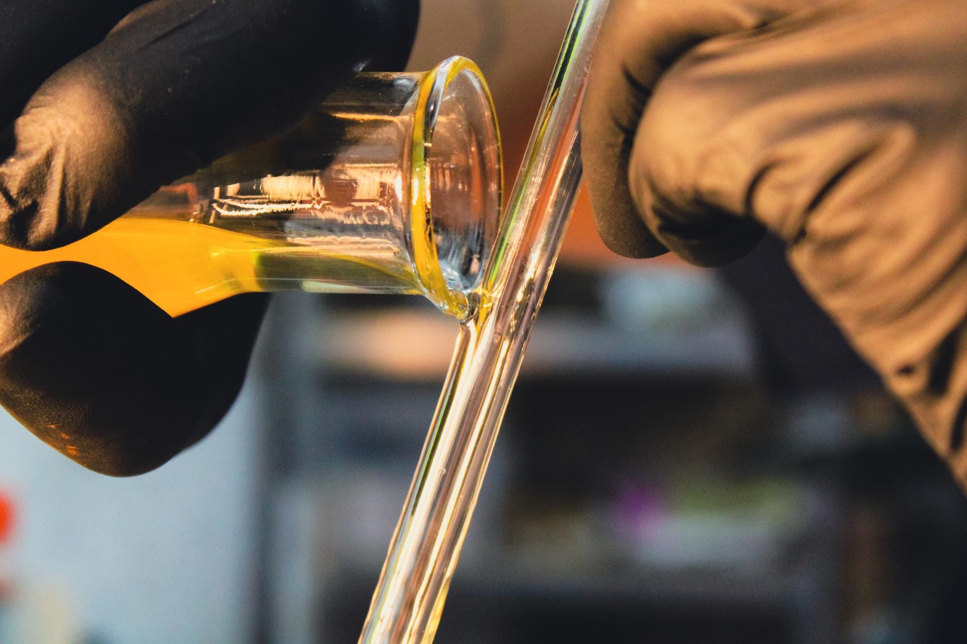 A chemist pouring a liquid onto a glass tube.