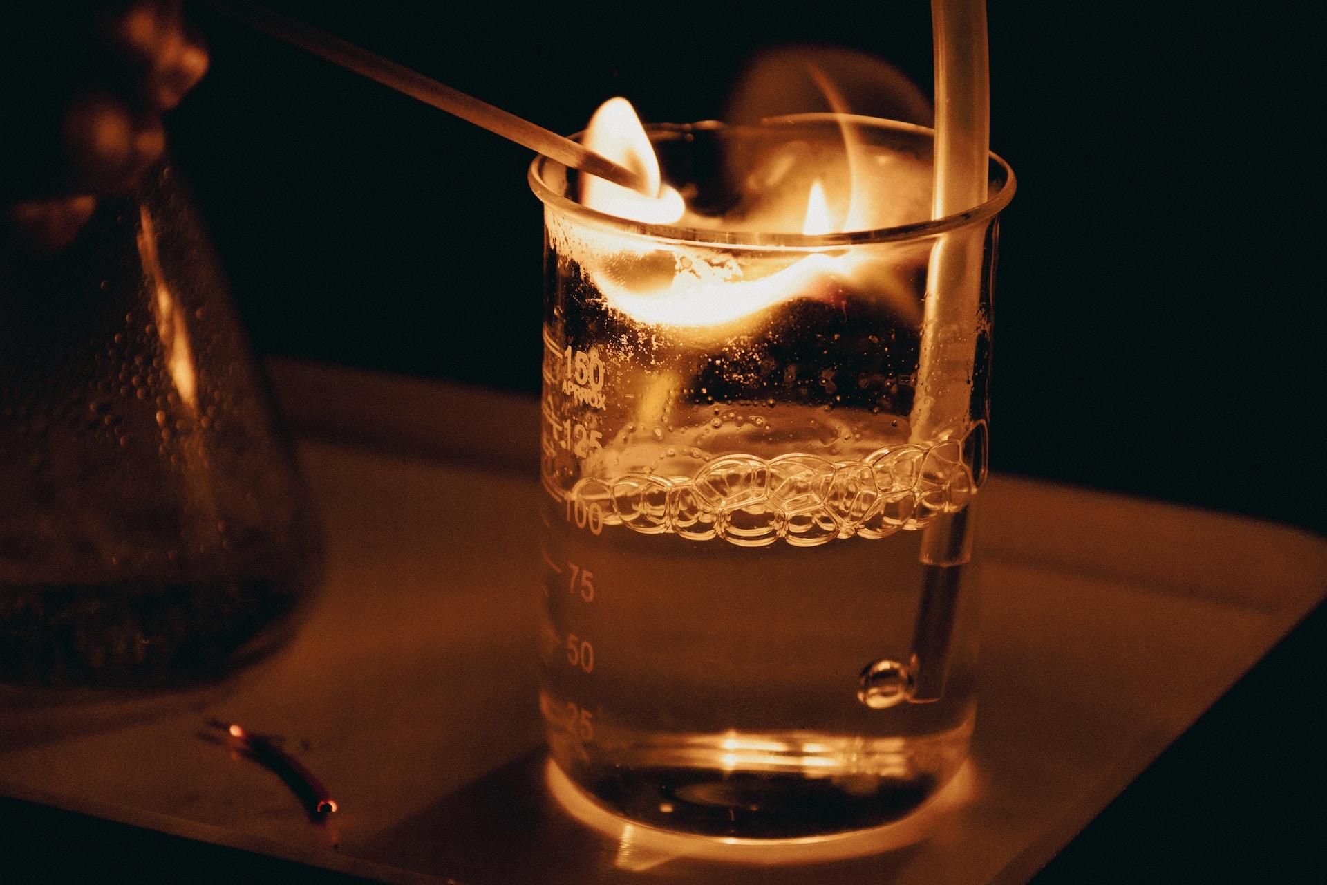 Chemistry glassware with a liquid being aerated and a flame.