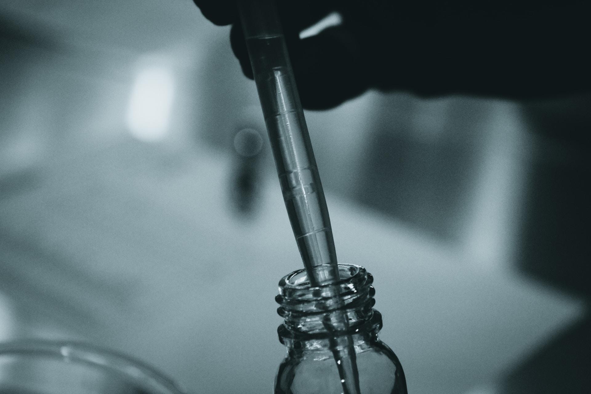 A liquid being put into a vial with a pipette.