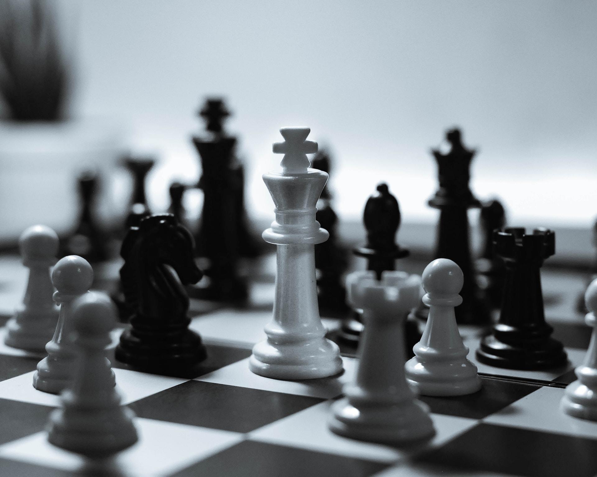 A white king surrounded by black pieces on a chess board.