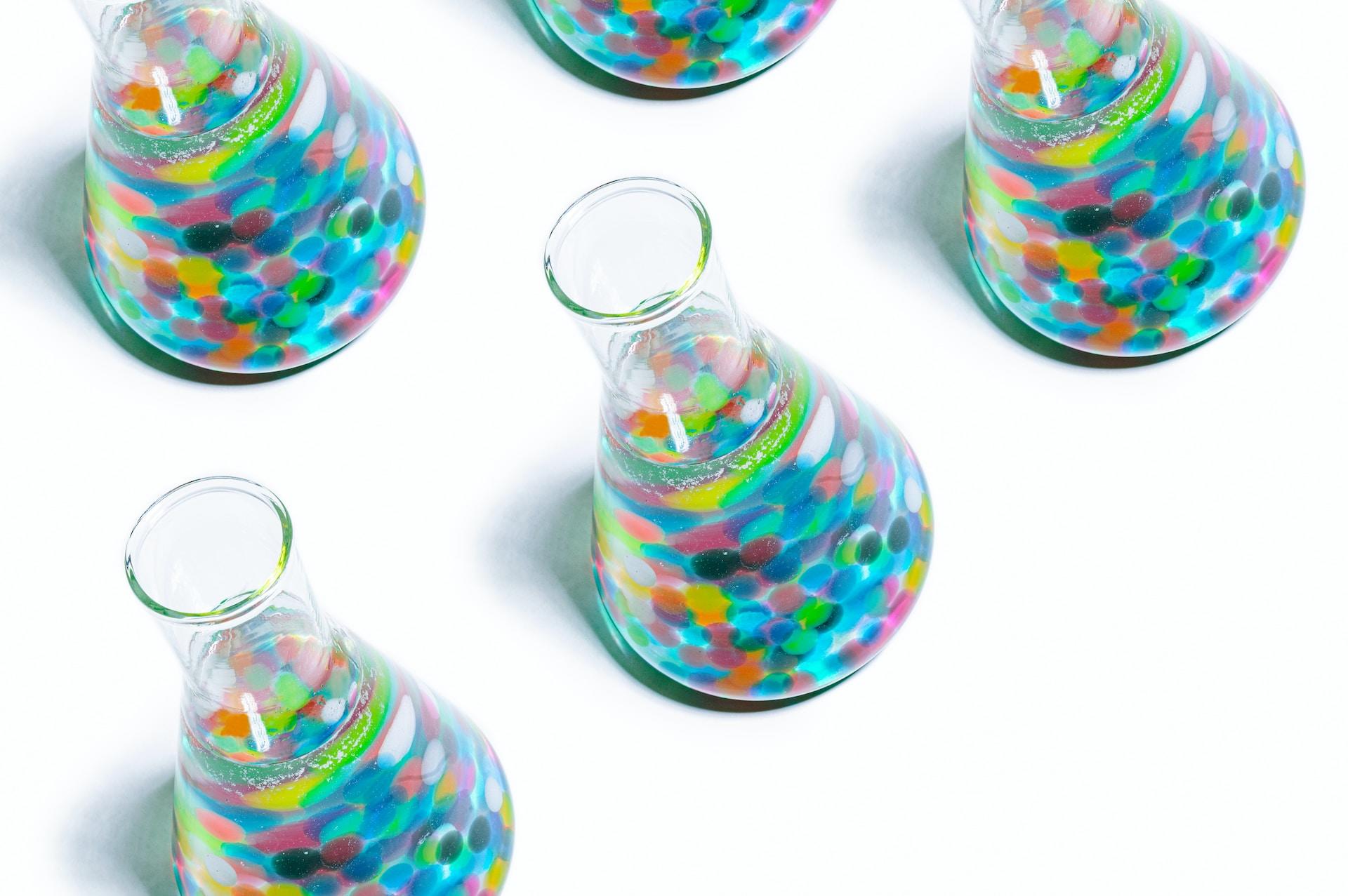 Various conical flasks with multicoloured liquids in them.
