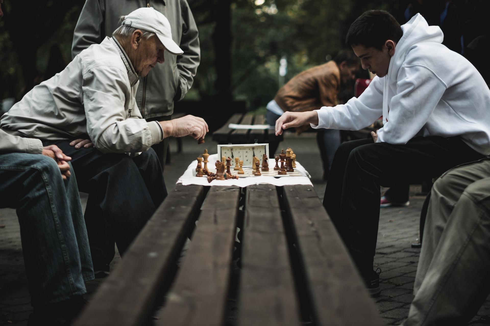 Two people playing chess in the park.