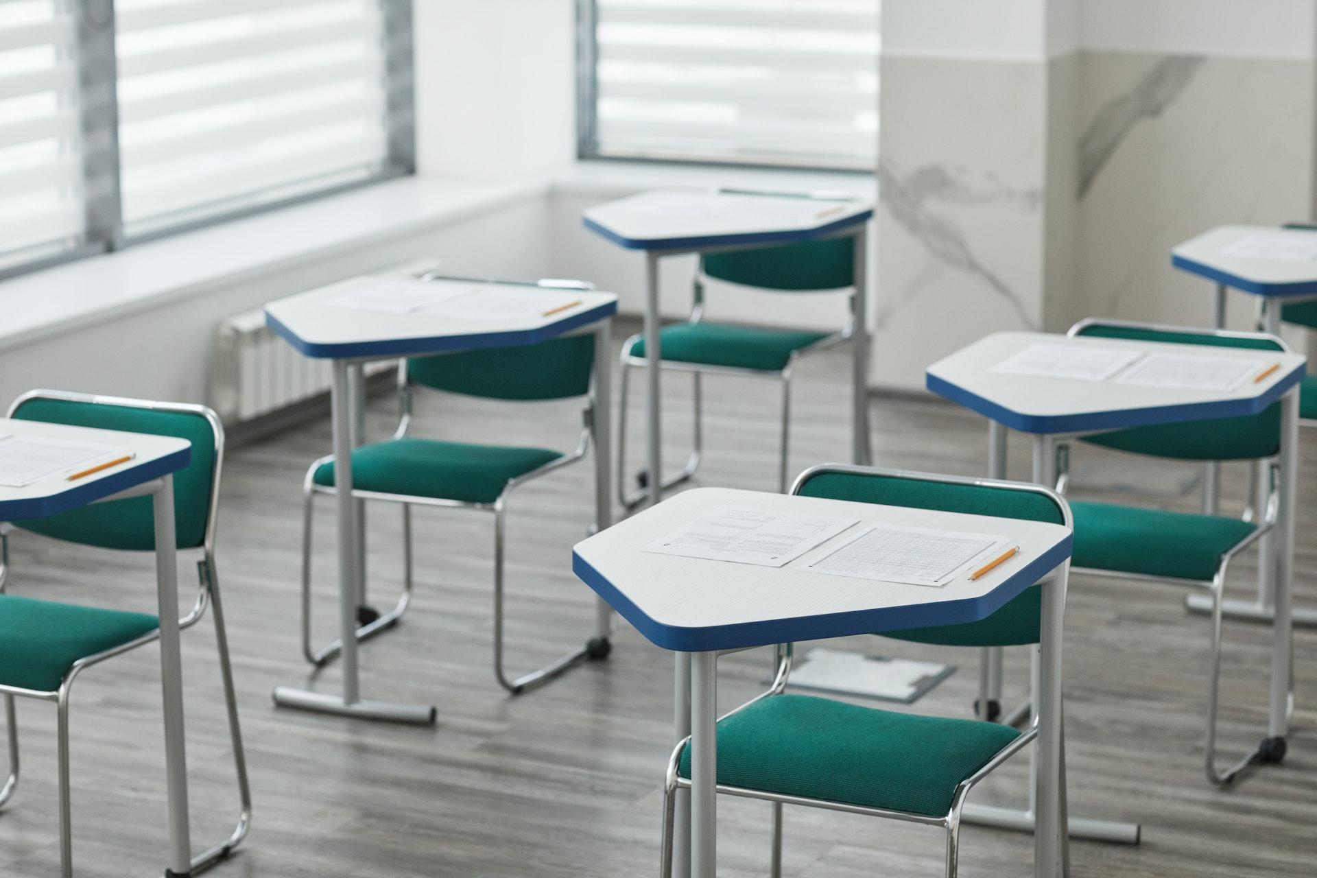 A classroom with desks that have test papers prepared for students on them.
