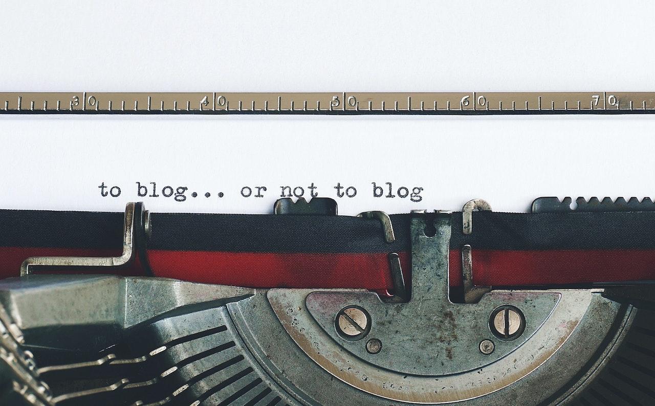 A close up of a sheet of paper in a typewriter that says "to blog... or not to blog"