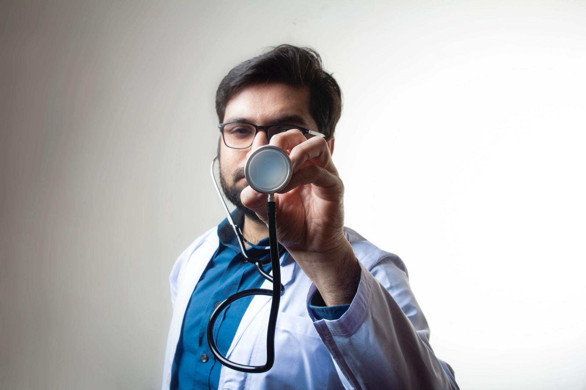A doctor holding out a stethoscope.