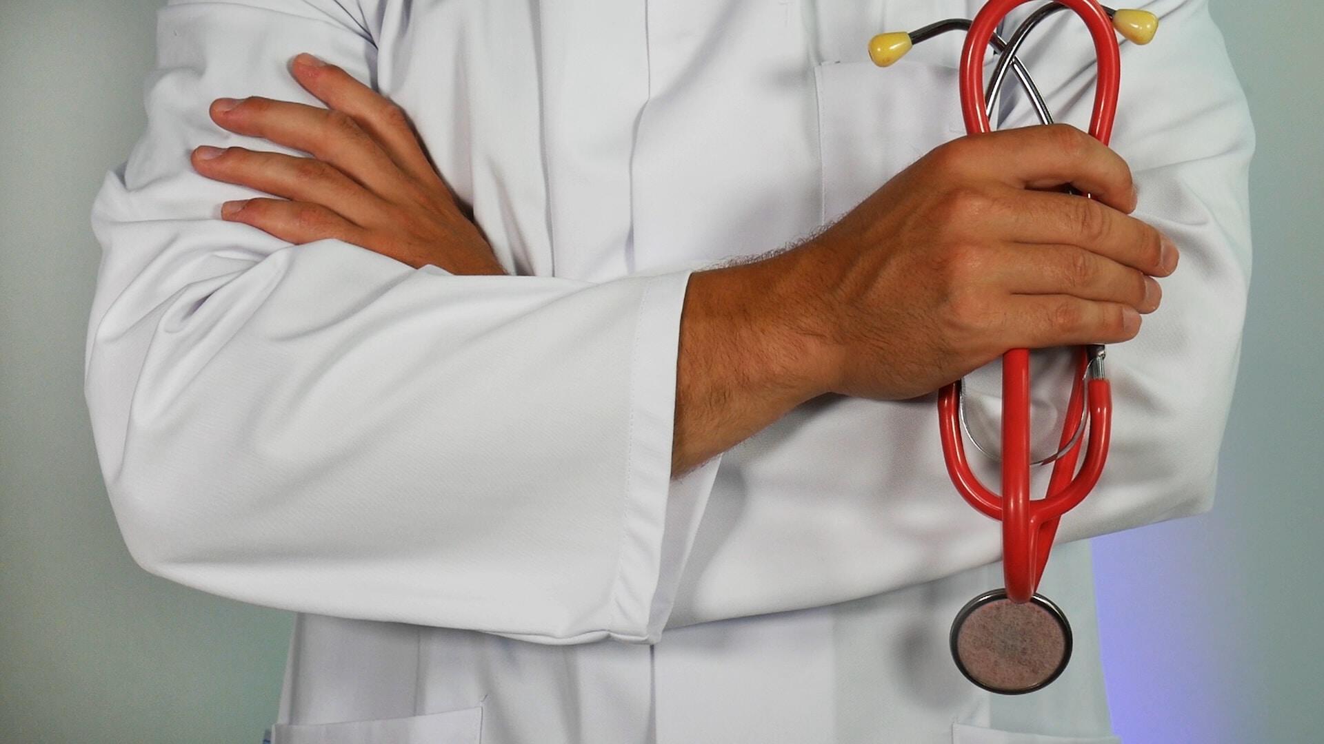 A doctor standing with a red stethoscope.