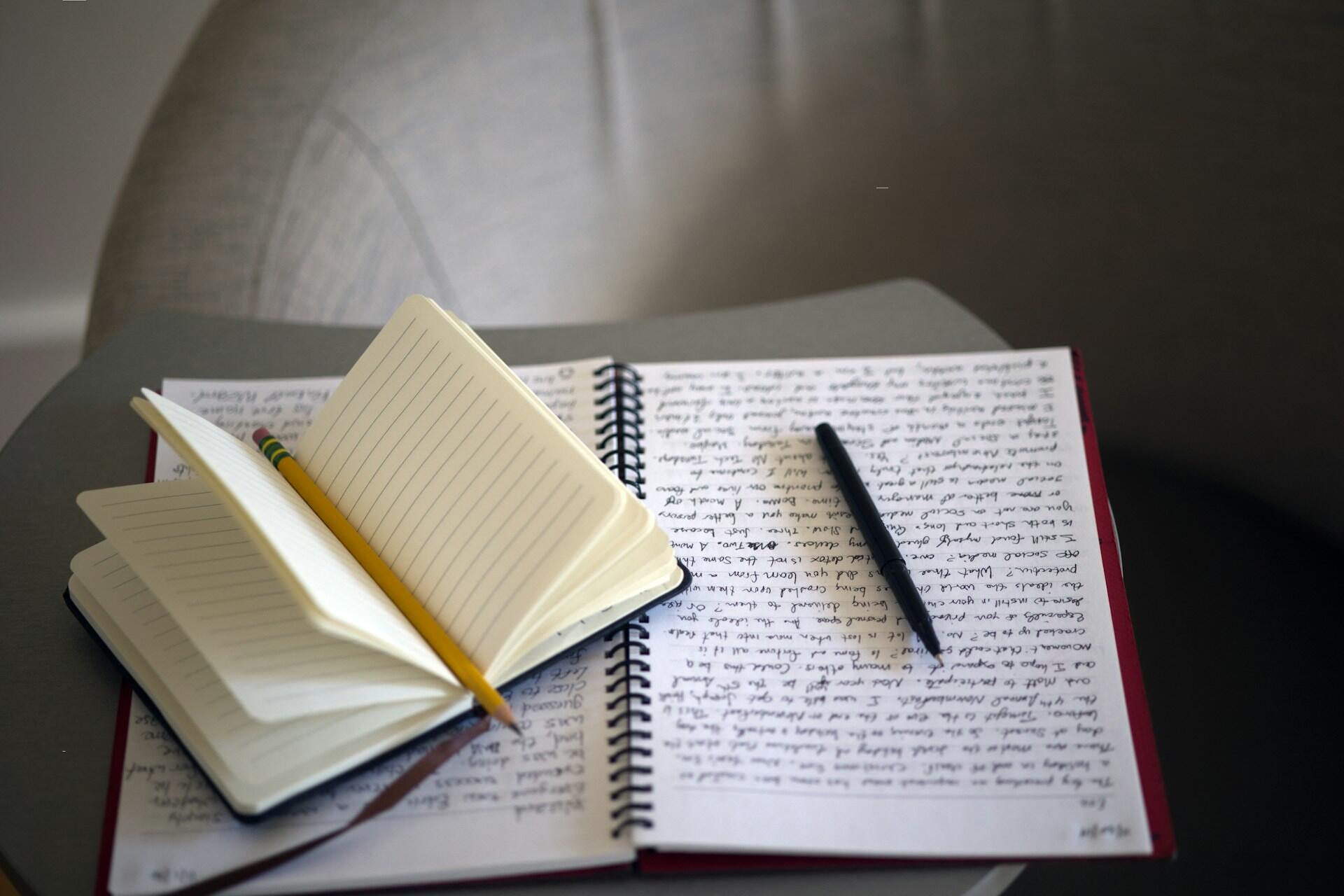 a notebook filled with neat handwriting in pen sits on a small table
