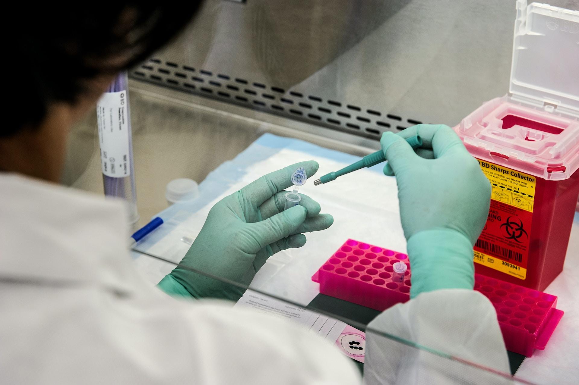 A scientist pipetting biological material into a container.