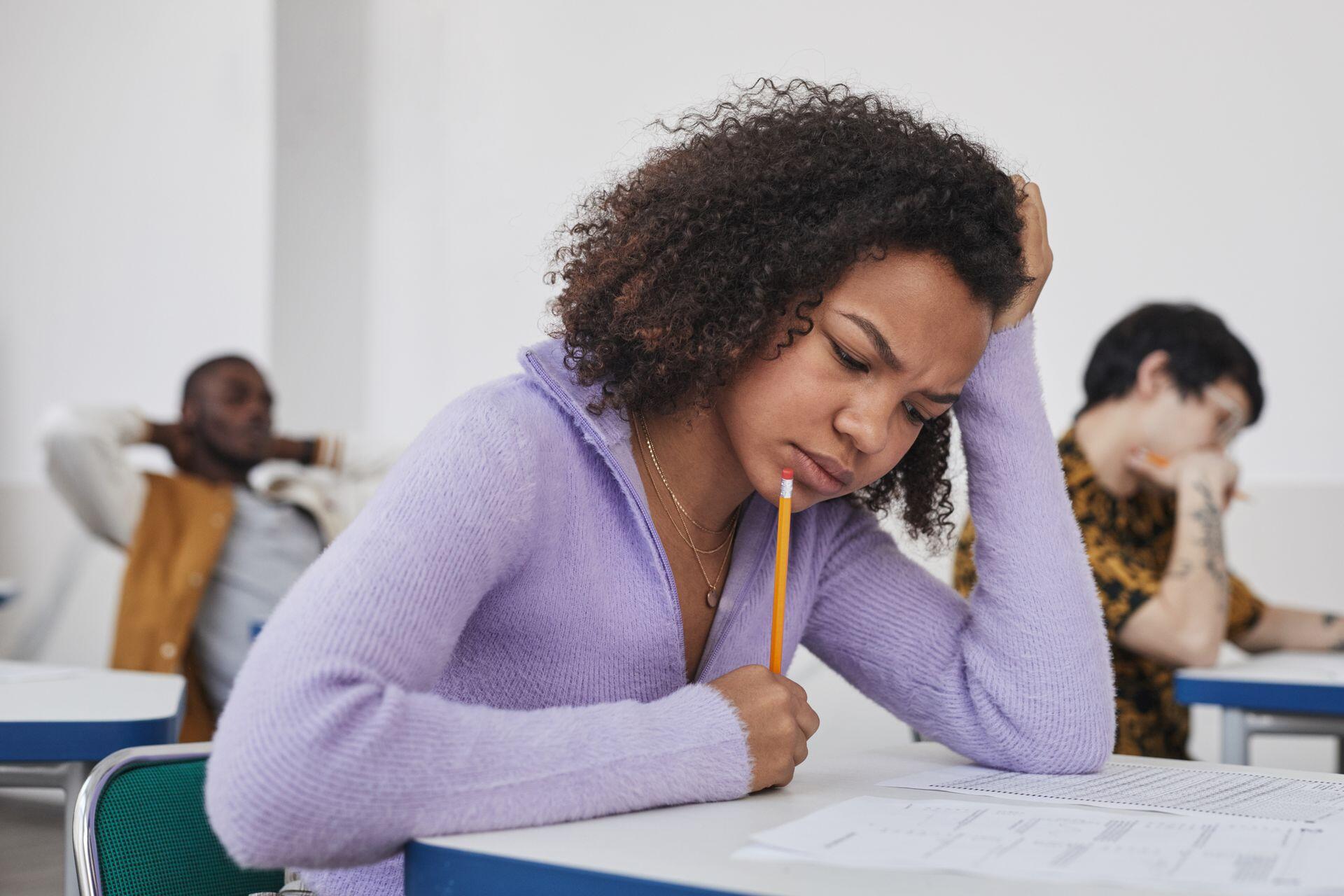 student sitting at a desk in class looking at their paper test with a confused expression